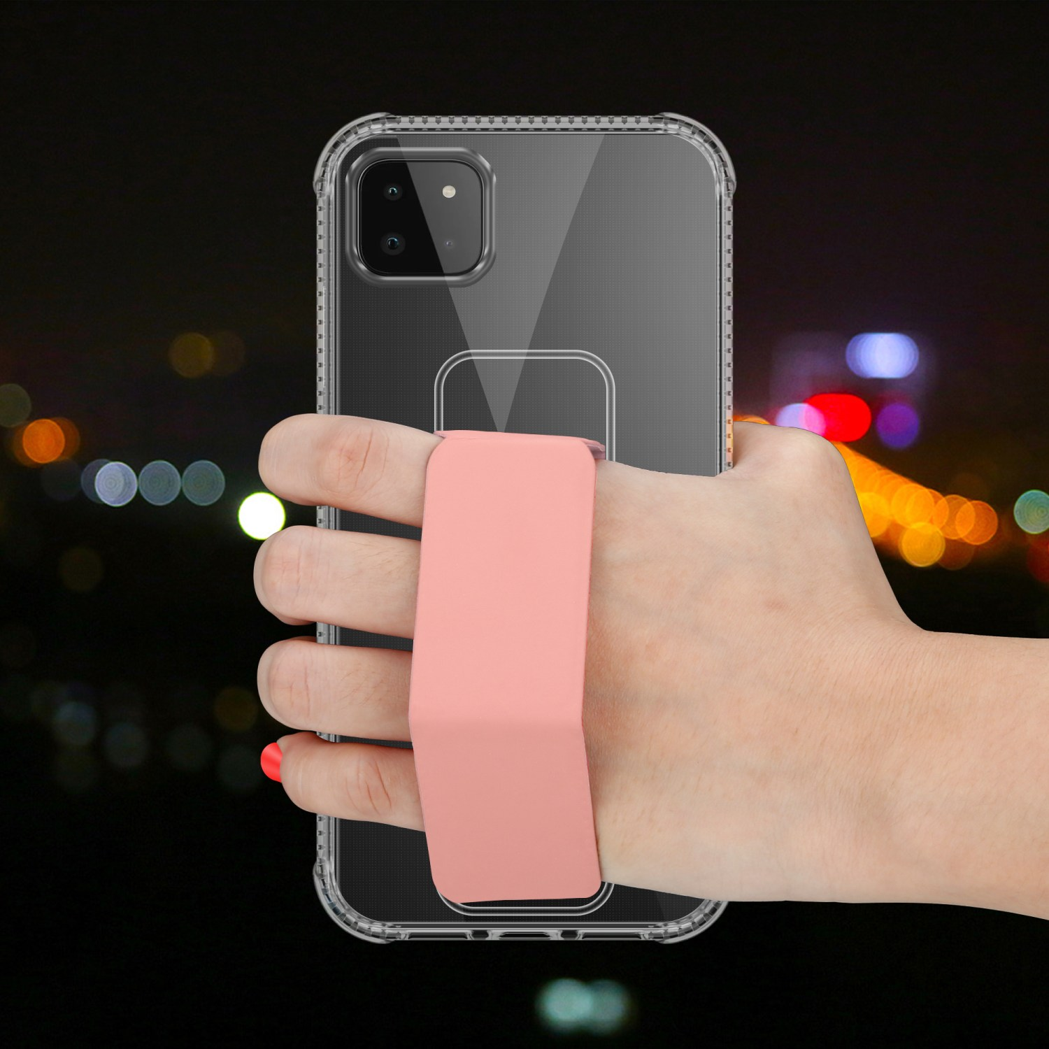 Hand hält eine klare Handyhülle mit pinkfarbenem Riemen vor verschwommenem Nachthintergrund.