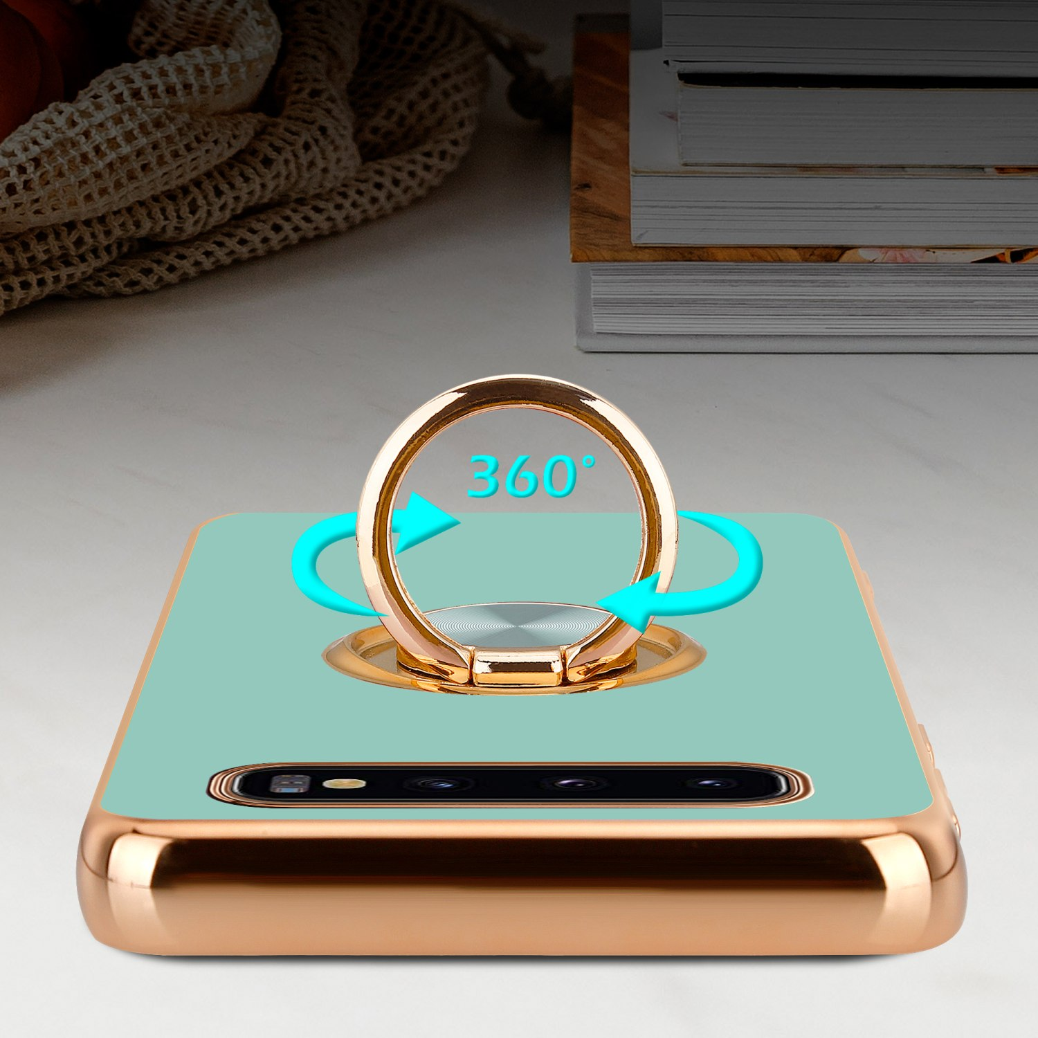 Una custodia per telefono con supporto ad anello girevole. Custodia verde acqua con dettagli dorati, frecce.