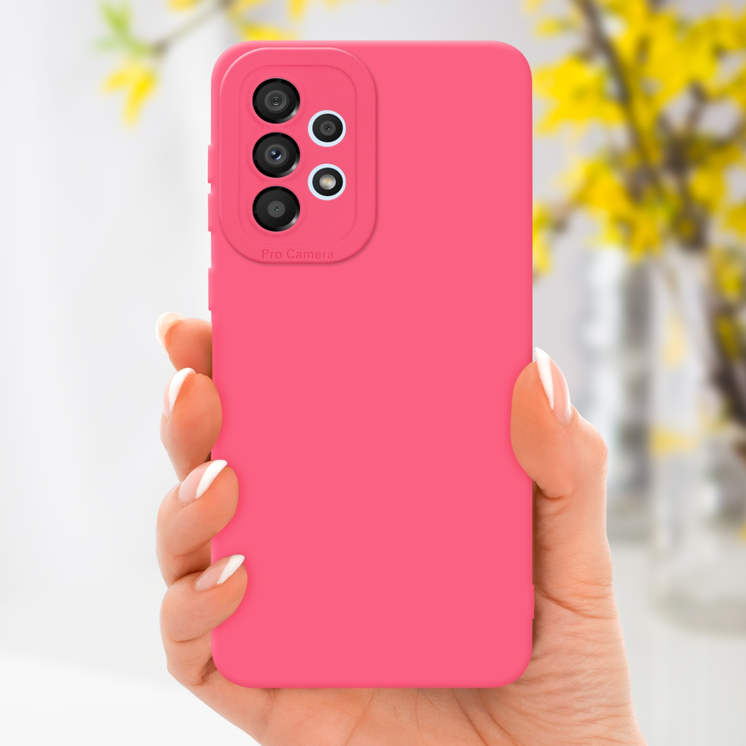 Mano che tiene una custodia per telefono rosa. Il telefono ha più lenti. Fiori gialli sullo sfondo.