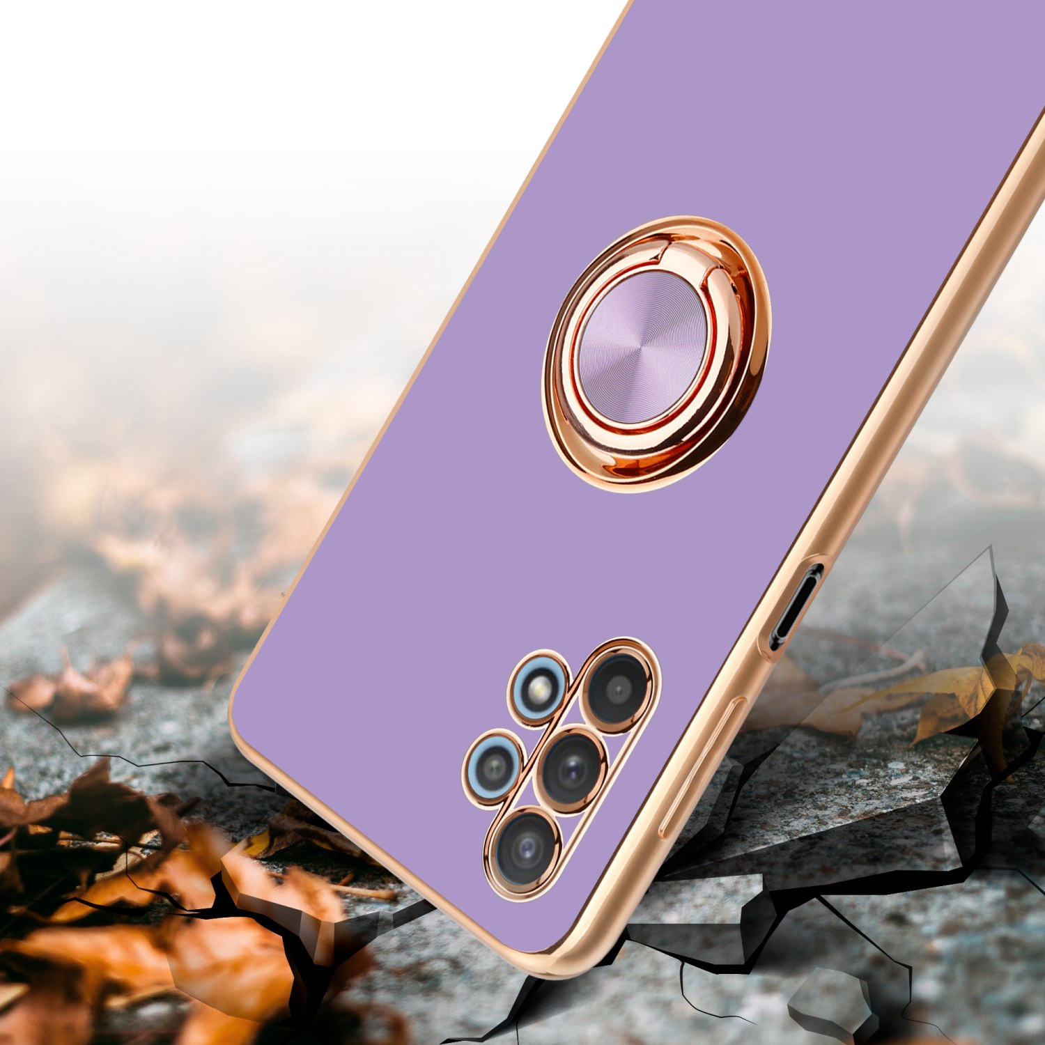 Una custodia viola per telefono con un anello dorato, su una superficie incrinata con foglie e cornice dorata.