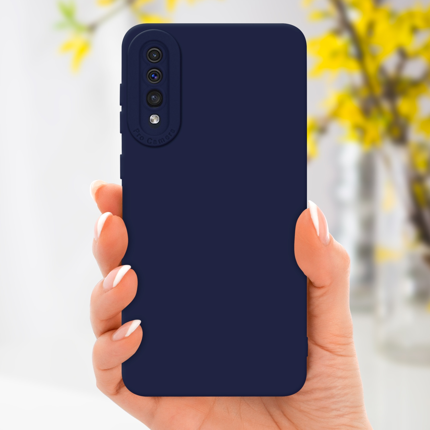 Main tenant une coque de téléphone bleu marine. Fleurs jaunes en arrière-plan, flou.