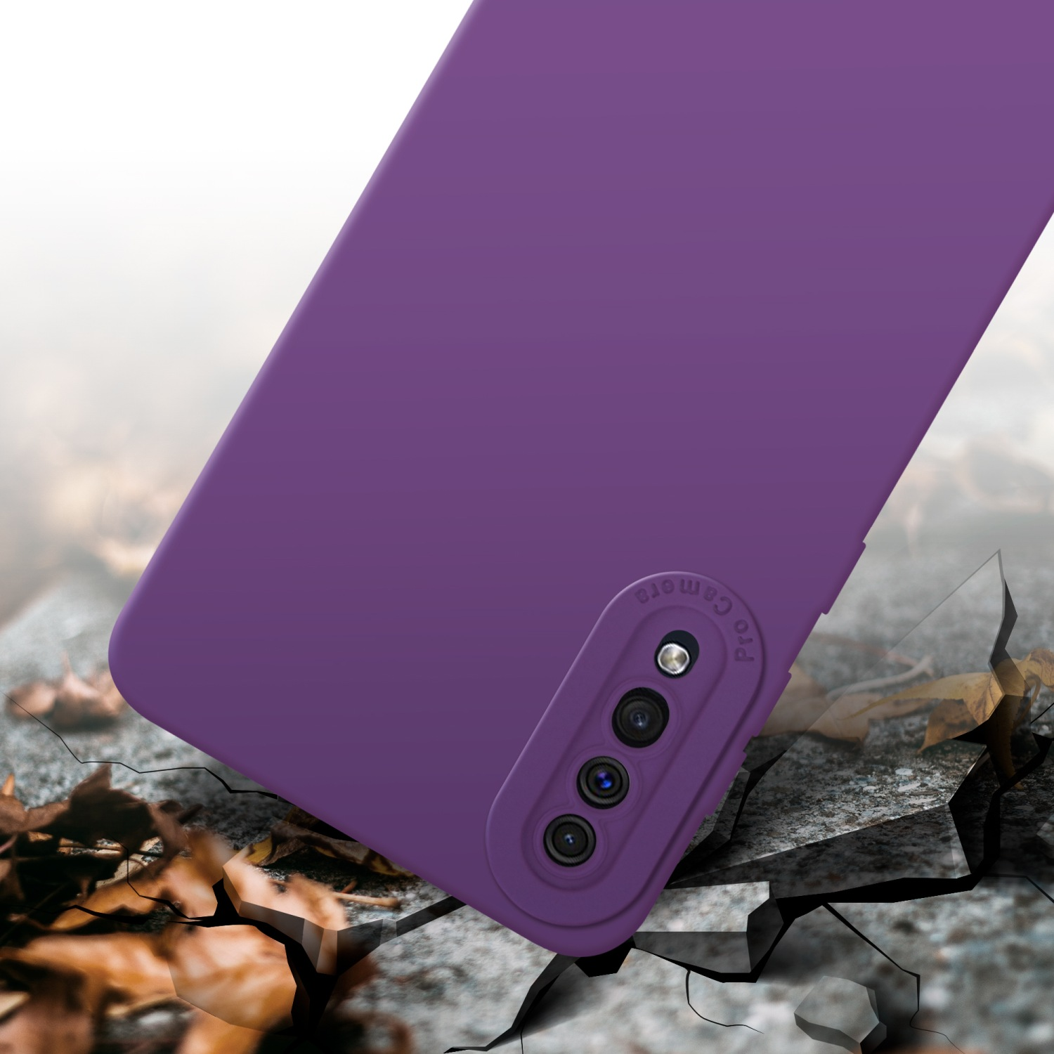 Coque de téléphone violette avec caméra, surface fissurée devant. Feuilles éparpillées devant.