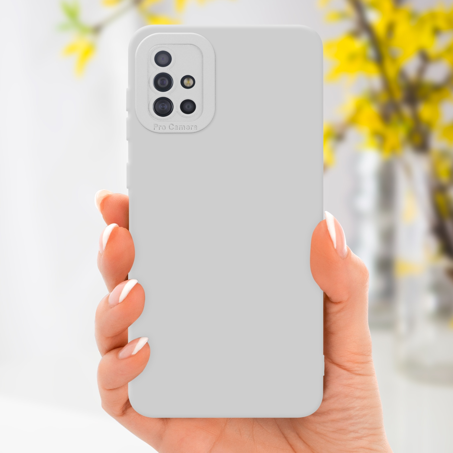 Main tenant une coque grise avec bosse de caméra. Fleurs dans un vase en arrière-plan.