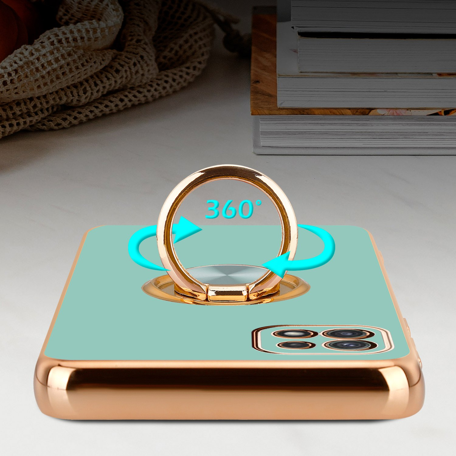 Eine Handyhülle mit Ringhalter. Die Hülle ist türkis mit einem goldenen Ring. Der Hintergrund ist verschwommen.