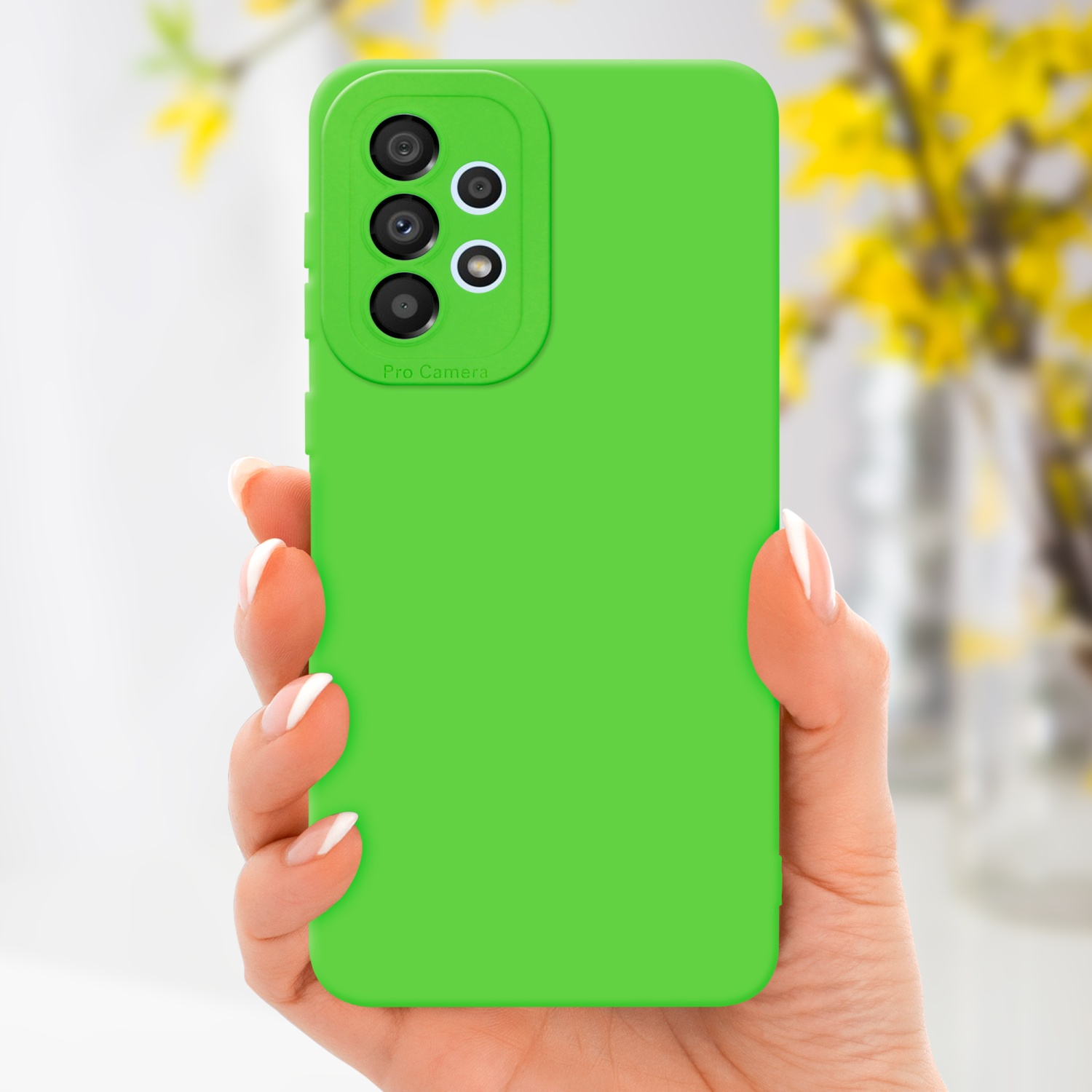 Una mano che tiene una custodia verde. Lo sfondo ha fiori gialli.