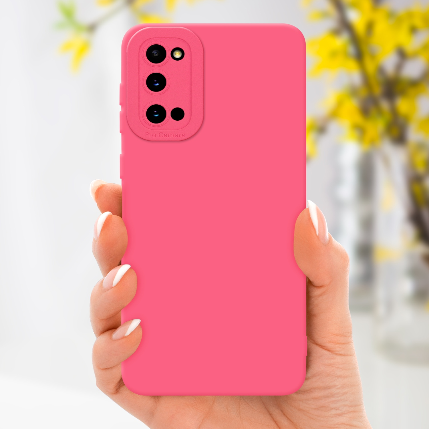 Main tenant une coque rose, vase de fleurs jaunes en arrière-plan.