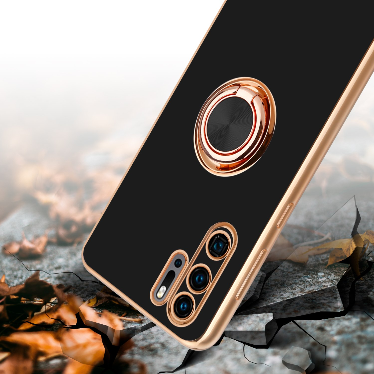 Schwarze Handyhülle mit goldenem Ringständer und Kameras, auf rissigem Boden, mit braunen Blättern.
