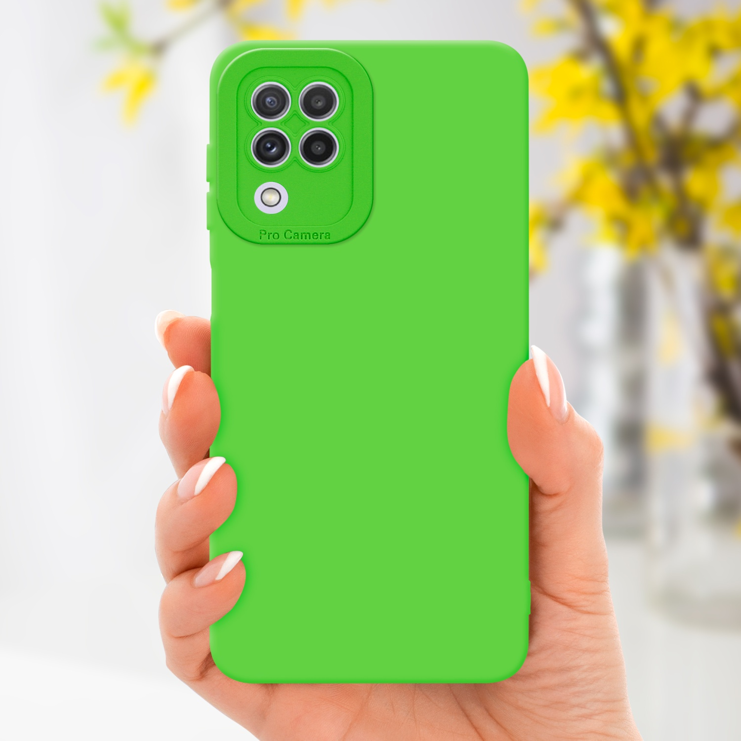 Mano che tiene una custodia verde per telefono con protezione fotocamera. Fiori gialli sullo sfondo.