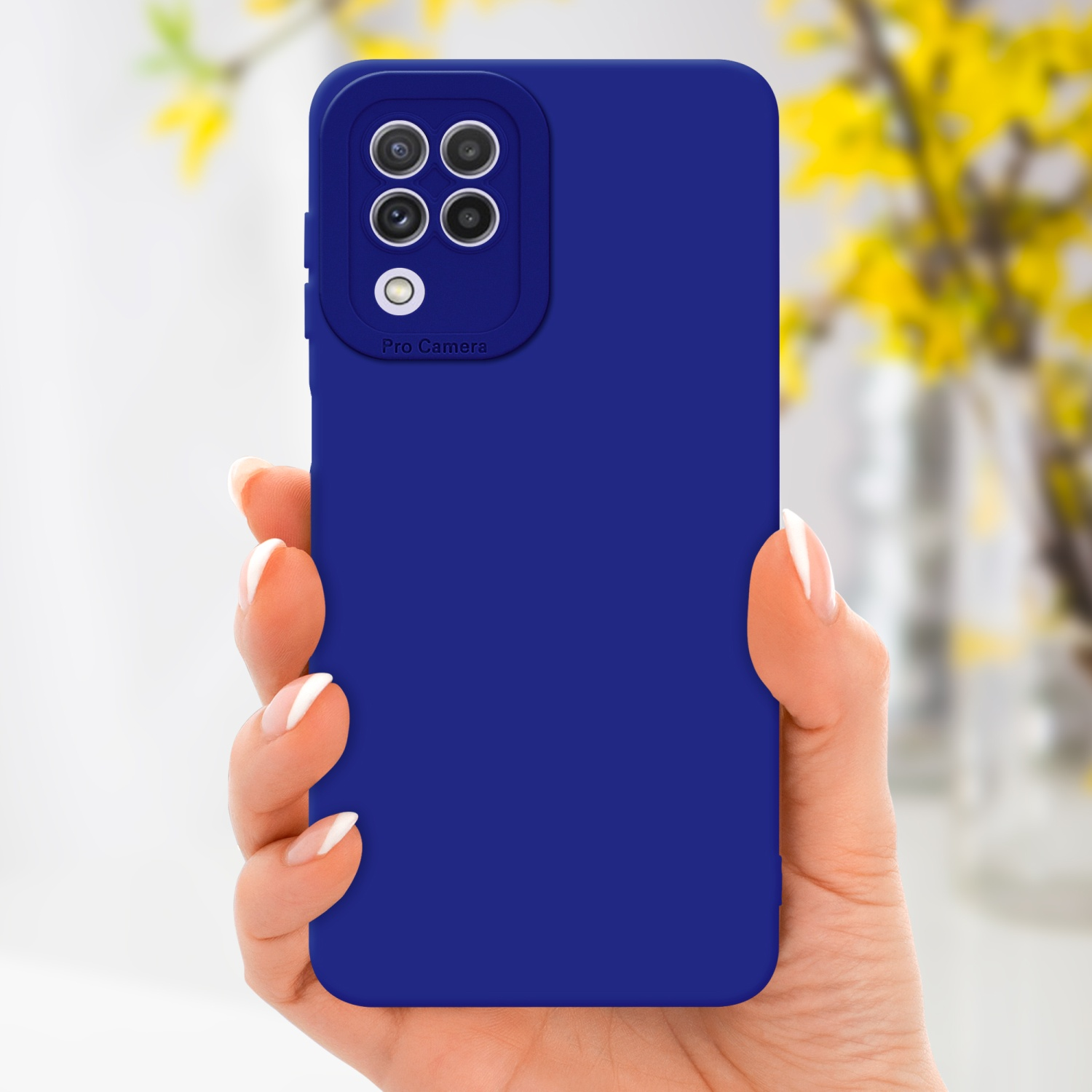 Una mano tiene una custodia per telefono blu con dettagli della fotocamera. Lo sfondo ha fiori sfocati.