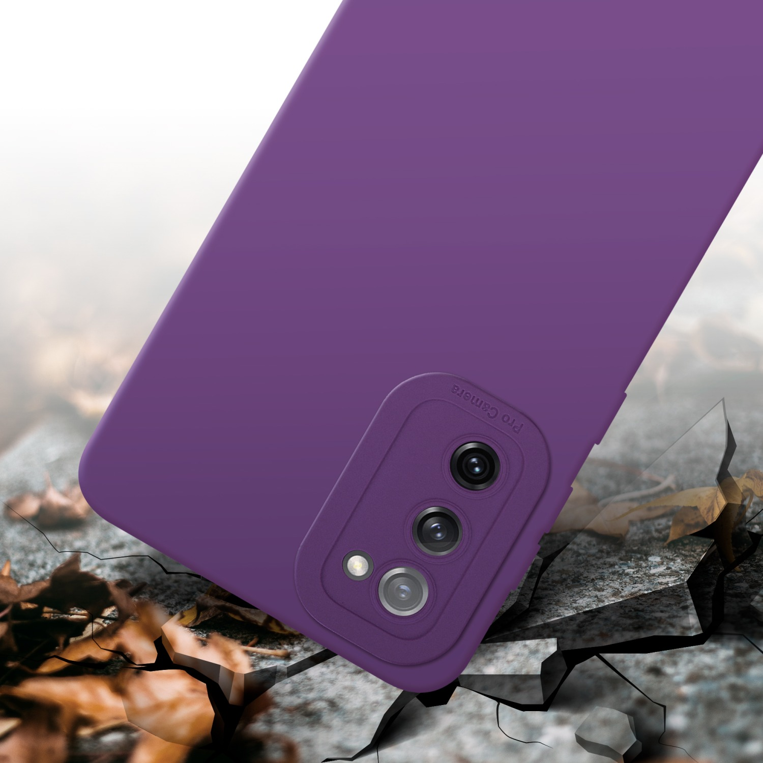 Custodia per telefono viola con lenti della fotocamera su un terreno crepato con foglie sparse.