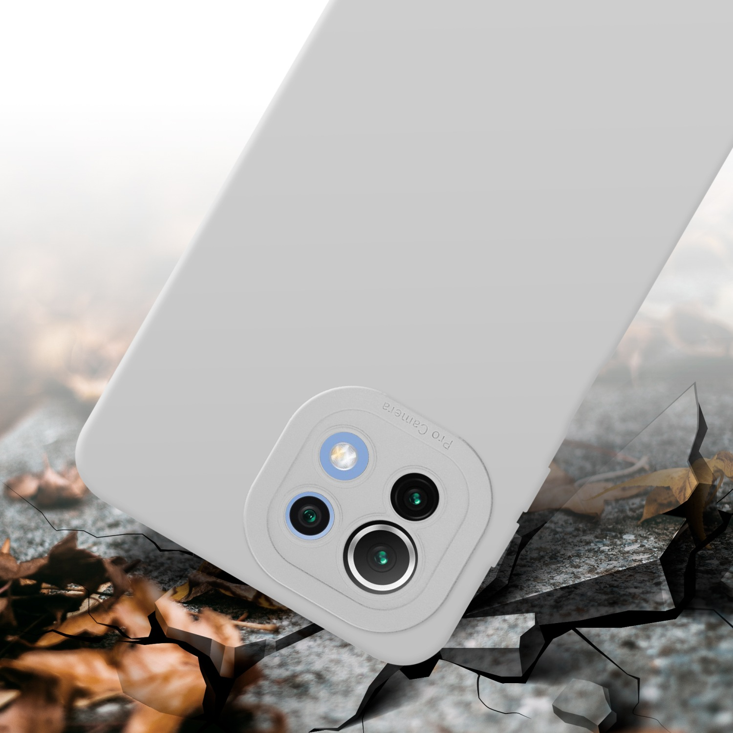 Una custodia per telefono grigio chiaro con modulo fotocamera è su una superficie incrinata, con foglie.