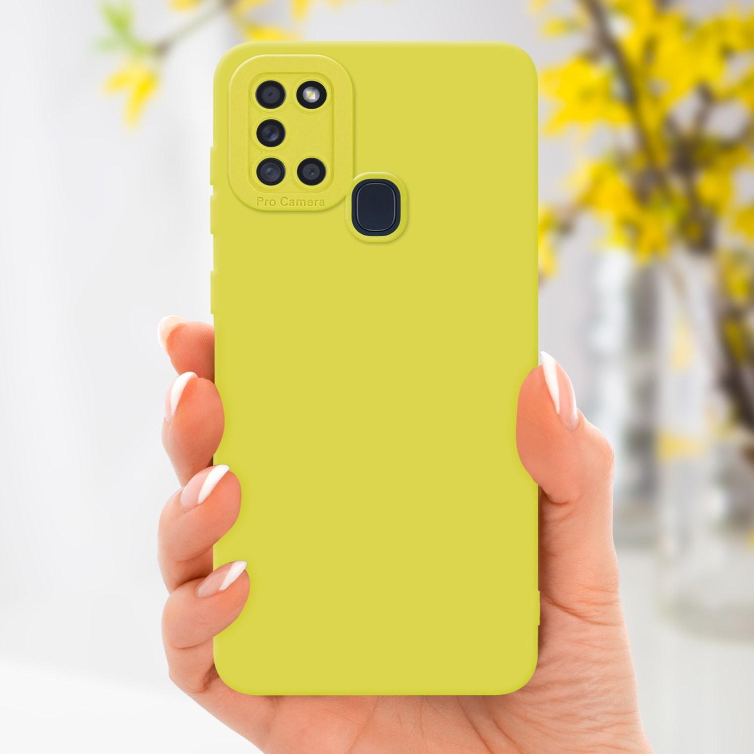Una mano tiene una custodia per telefono gialla con dettagli della fotocamera. Lo sfondo ha fiori sfocati.