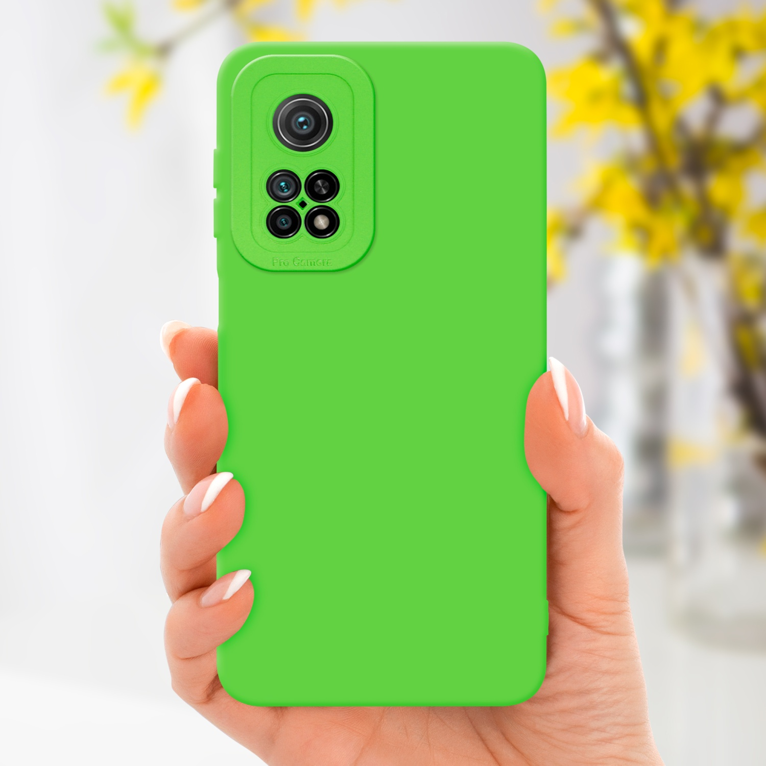 Custodia verde per telefono con fotocamera. Mano che la tiene. Fiori gialli sfocati sullo sfondo.