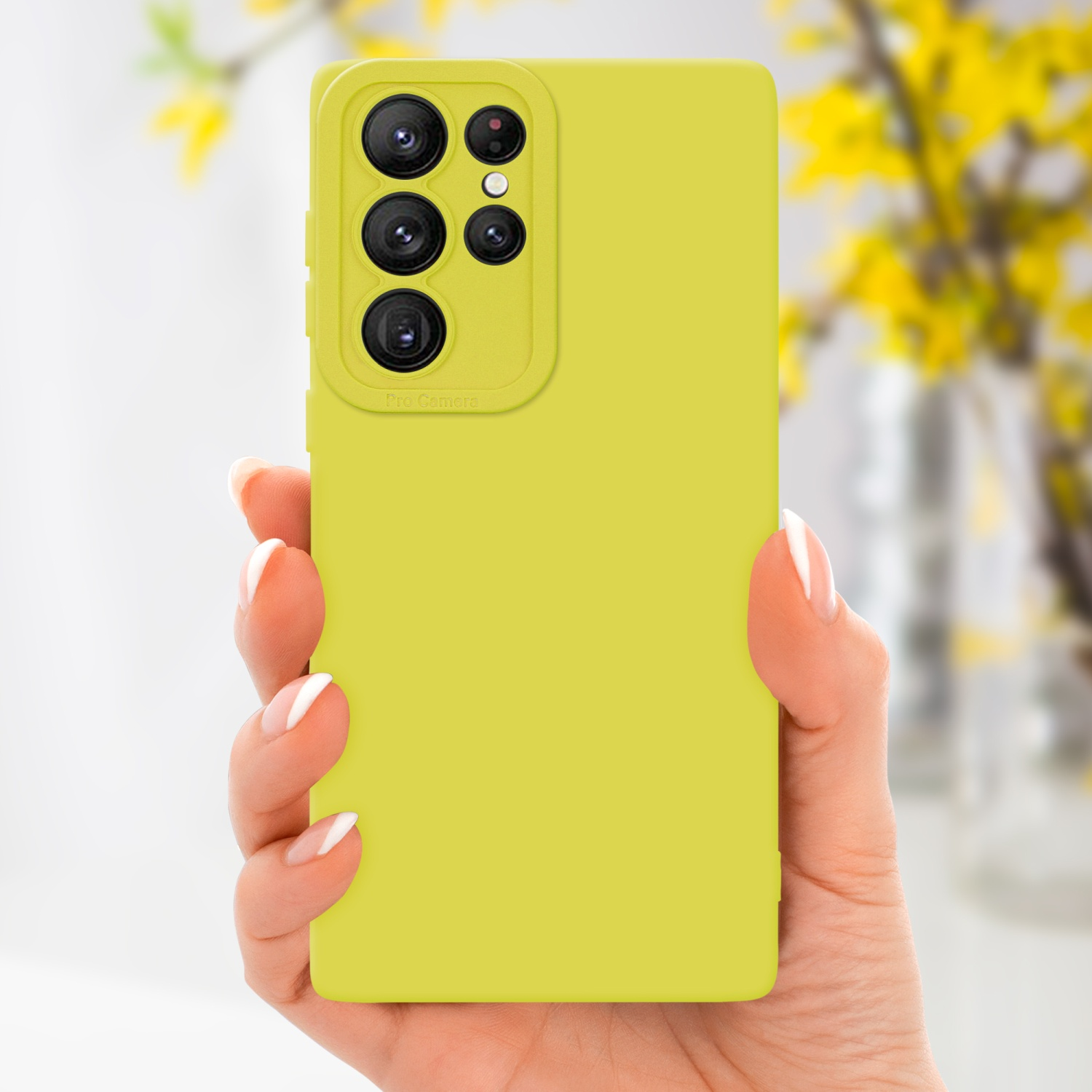 Mano che tiene una custodia gialla per telefono con un ritaglio per la fotocamera. Sfondo con fiori gialli.