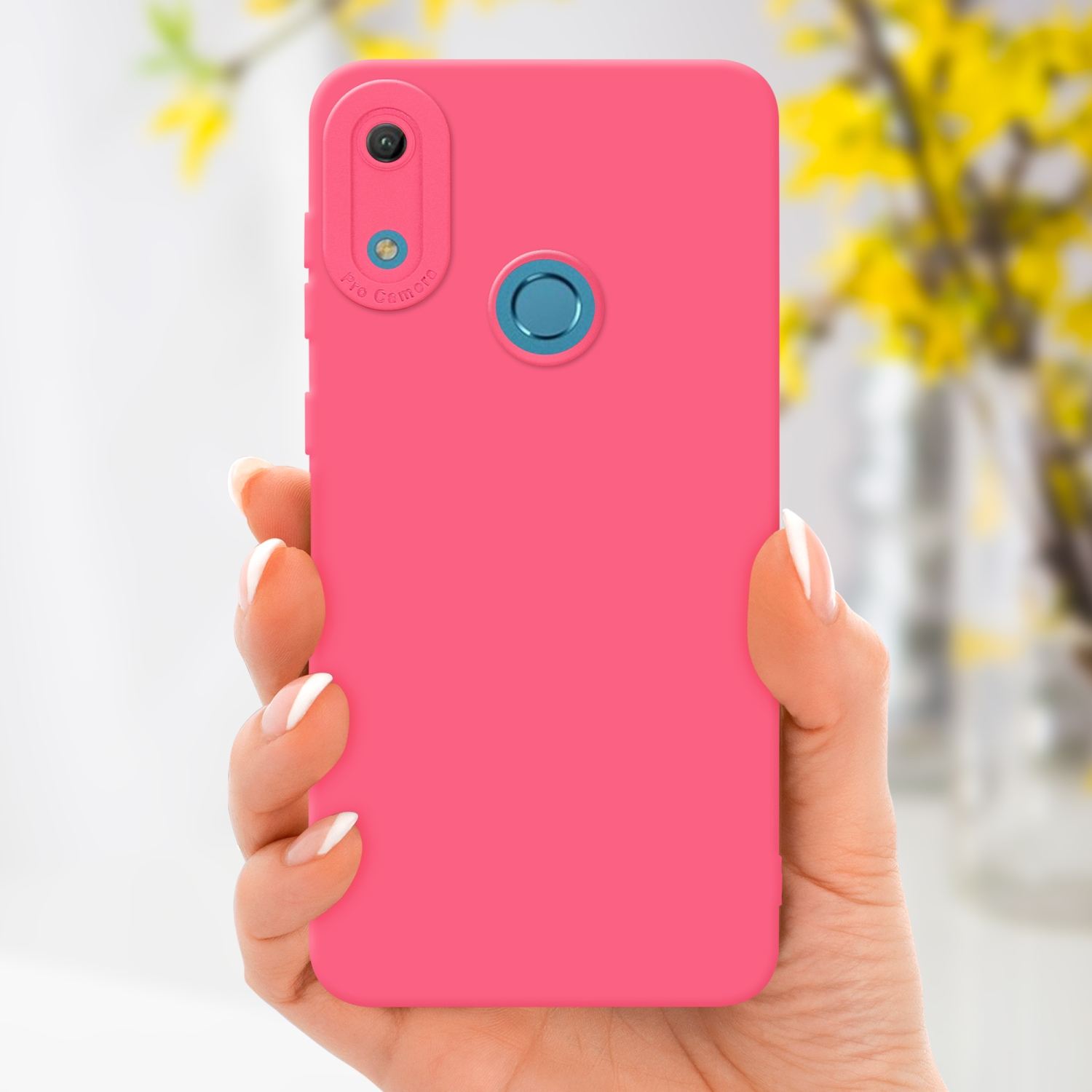 Main tenant une coque de téléphone rose. Fleurs jaunes en arrière-plan flou. Détail de l'appareil photo.