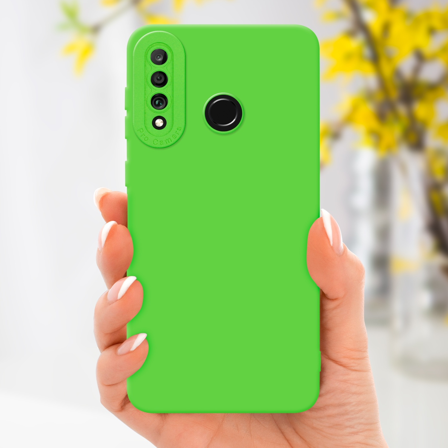 Mano che tiene una custodia verde. Fiori gialli e vaso sullo sfondo.
