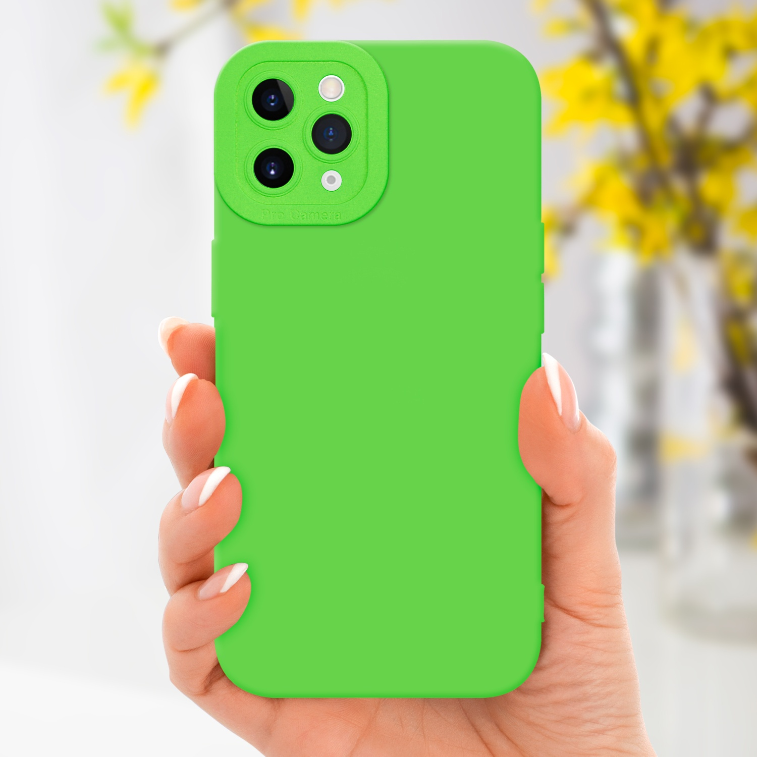 Custodia verde con array di fotocamere, tenuta in mano, con fiori sullo sfondo.