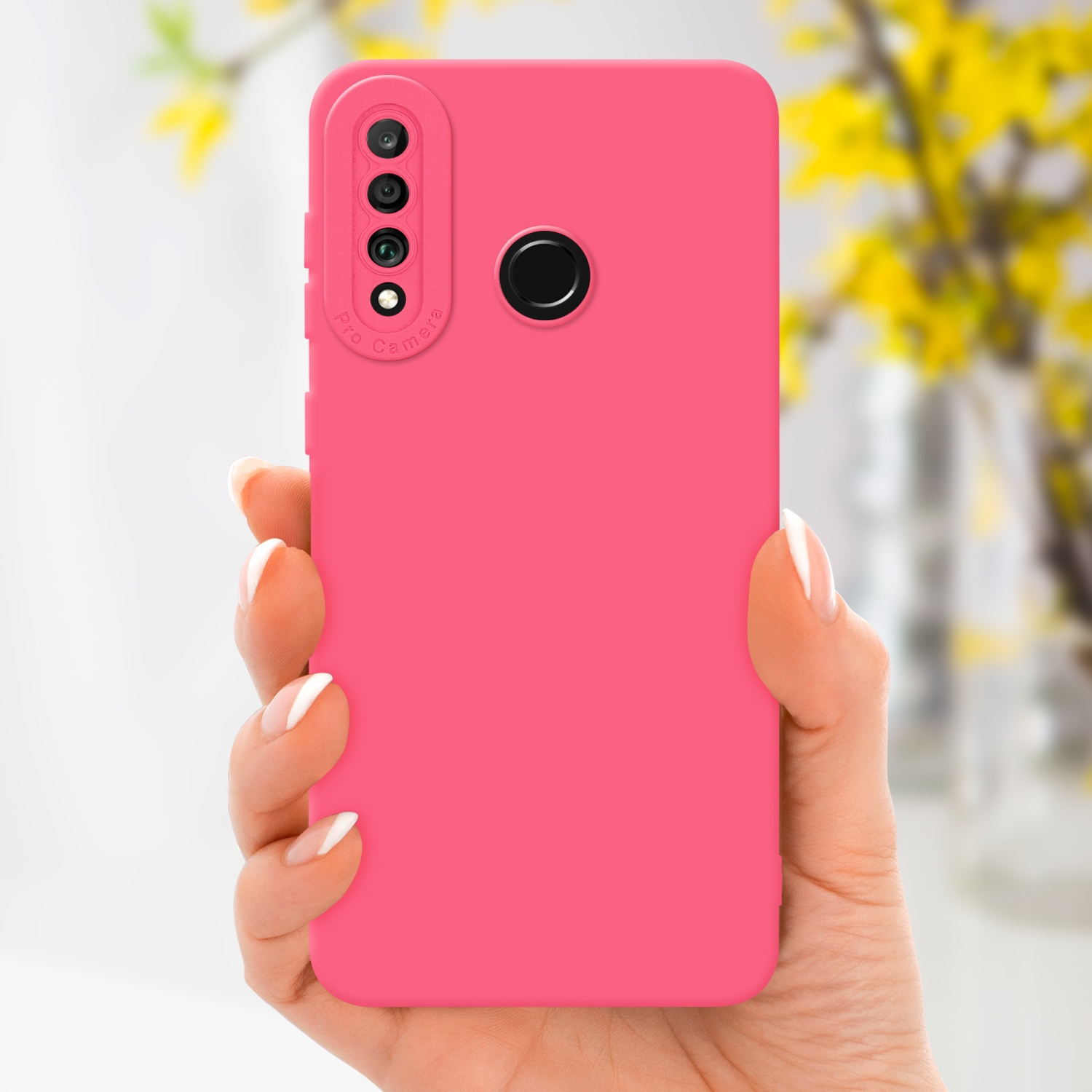 Mano che tiene una custodia rosa con un rigonfiamento della fotocamera. Fiori gialli sfocati sullo sfondo.