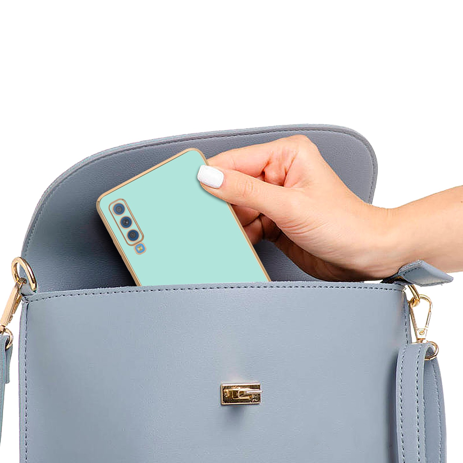 Hand hält ein Telefon in einer hellblauen Handtasche. Weißer Hintergrund.