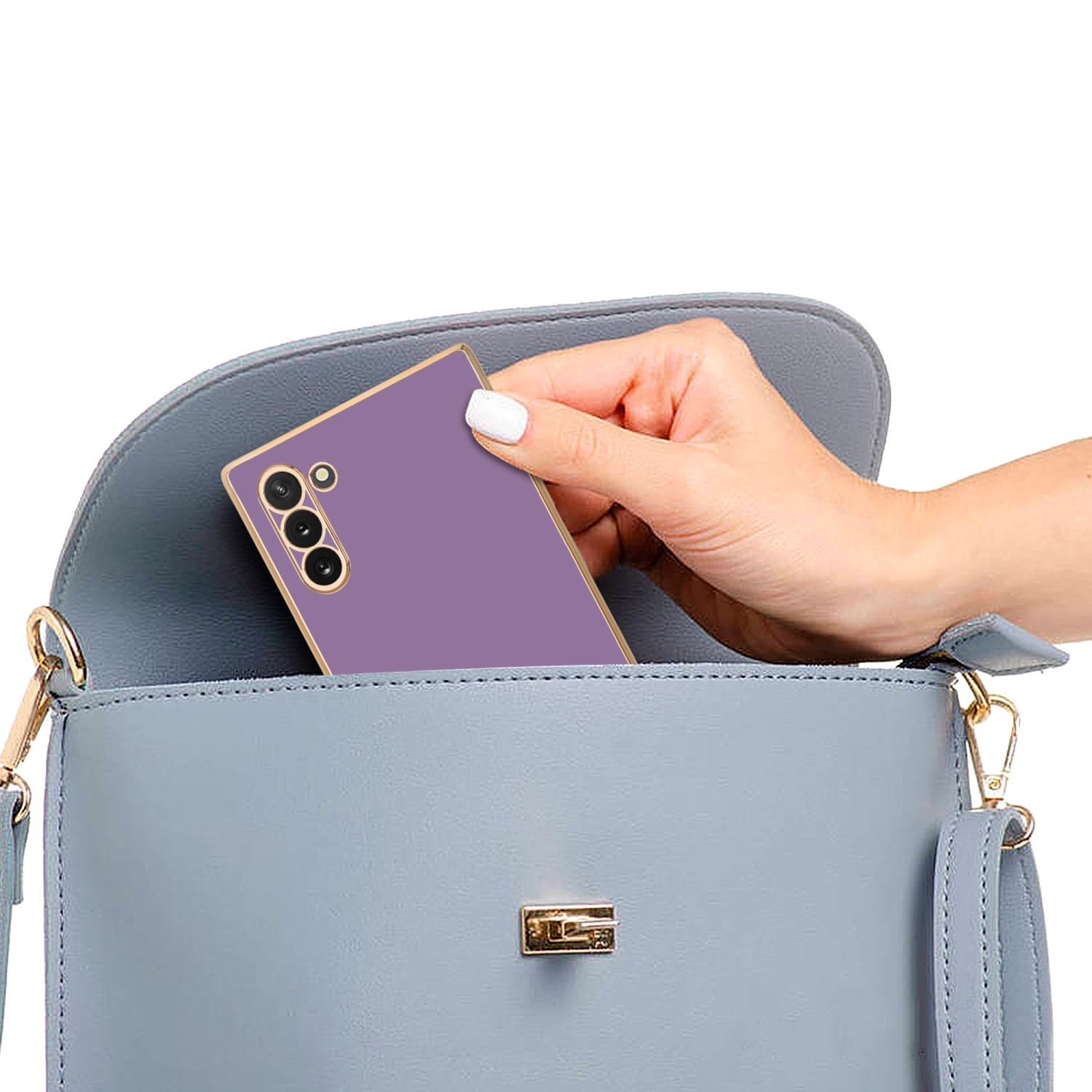 Eine Hand legt ein lila Telefon in eine hellblaue Handtasche, mit weißem Hintergrund.