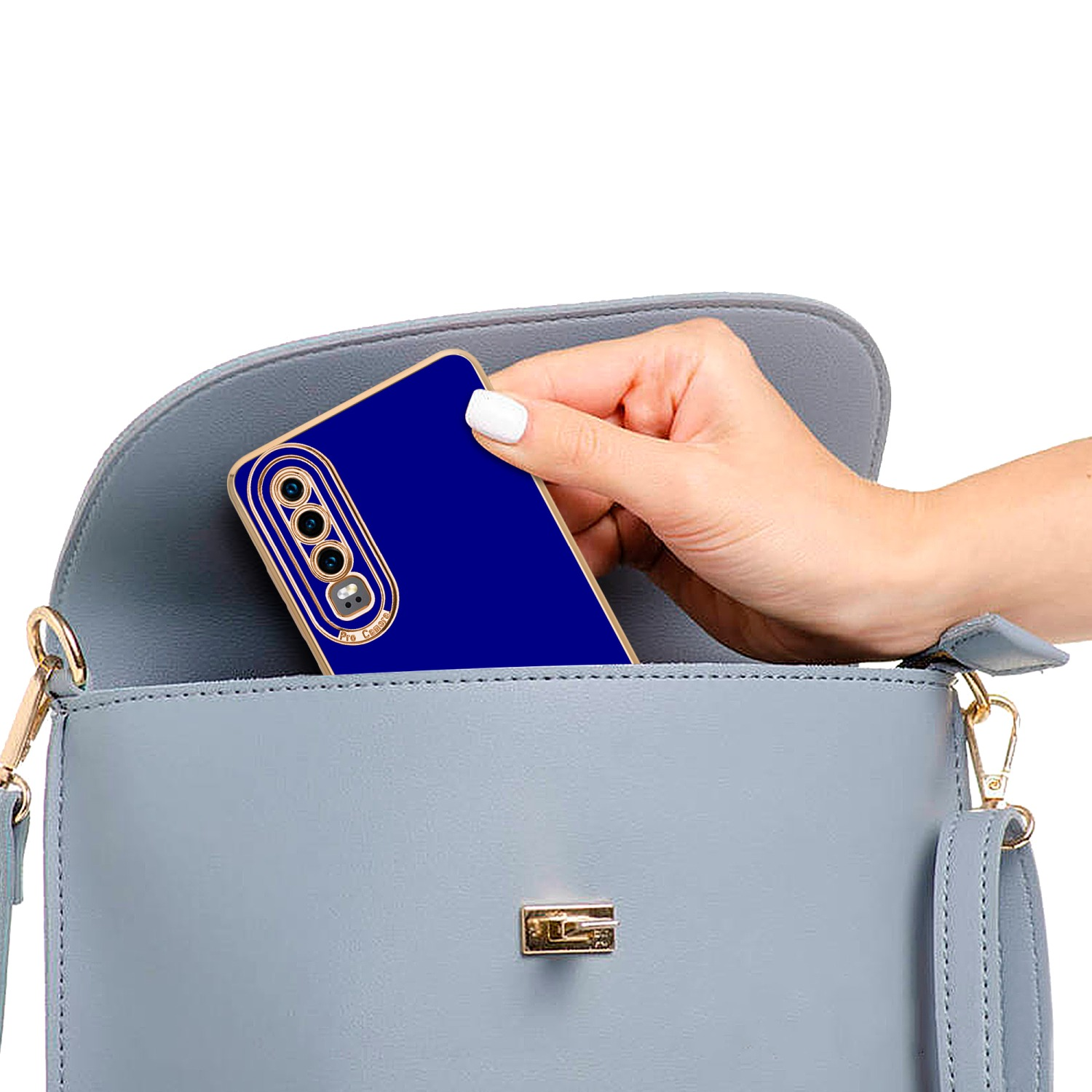 Hand legt blaues Telefon in graue Handtasche. Das Telefon hat eine goldene Kamera.