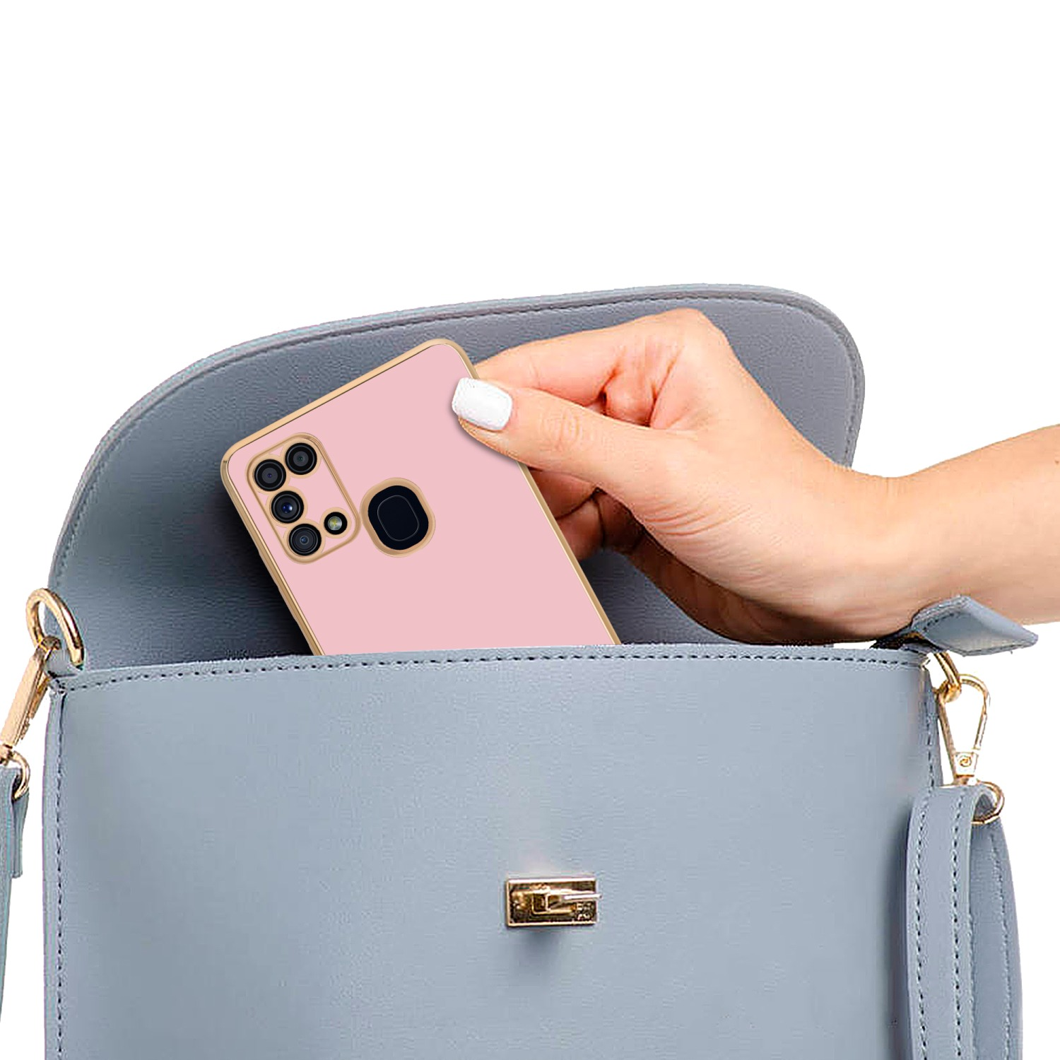 Eine Hand legt ein rosa Telefon mit goldenem Rahmen in eine hellblaue Handtasche.