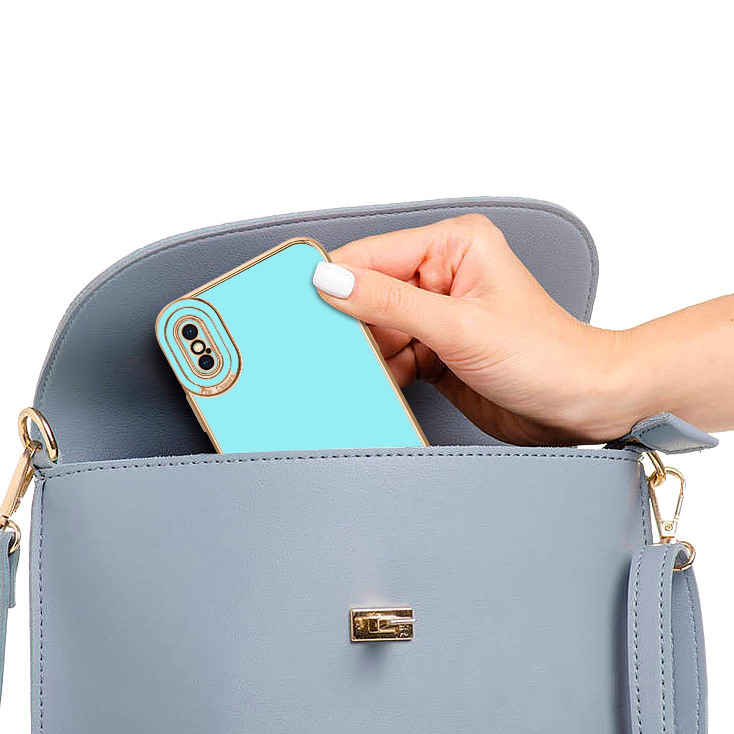 Eine Hand legt eine blaue Handyhülle in eine graue Handtasche. Goldener Kameraring.