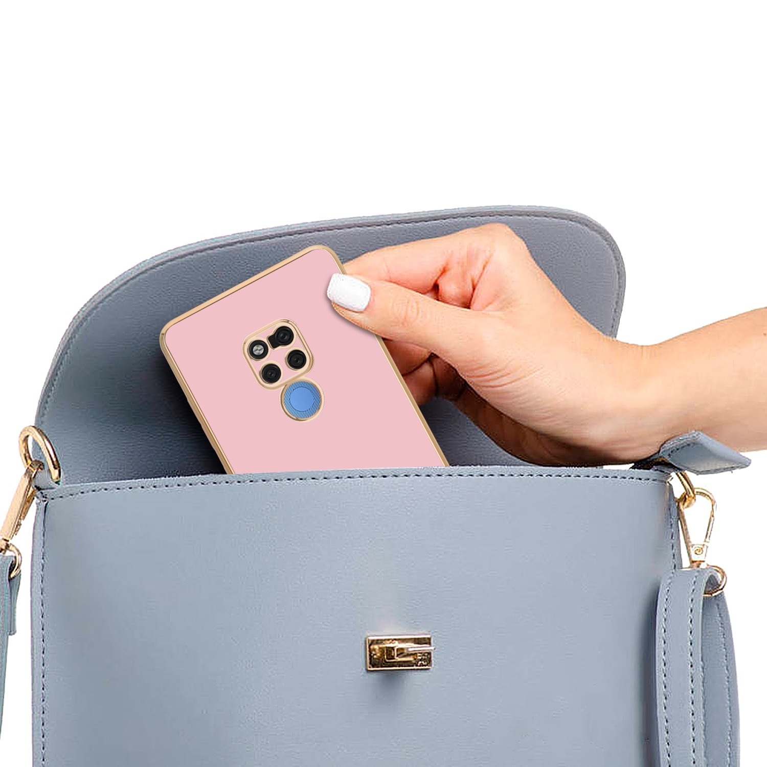 Hand legt eine rosa Handyhülle in eine graue Handtasche. Die Tasche hat einen goldenen Rahmen.