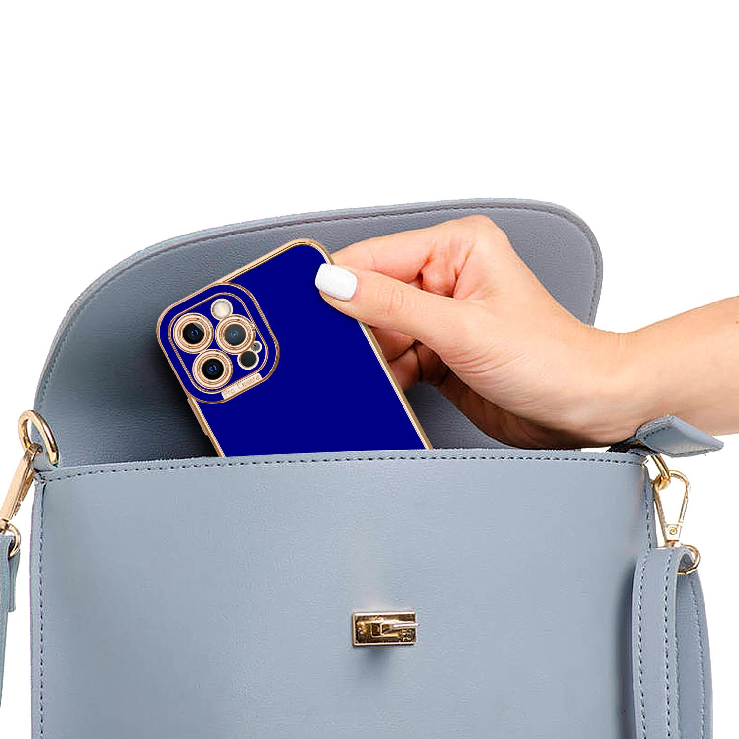 Eine Hand legt eine blaue Handyhülle in eine graue Handtasche. Die Hülle hat einen goldenen Rand.