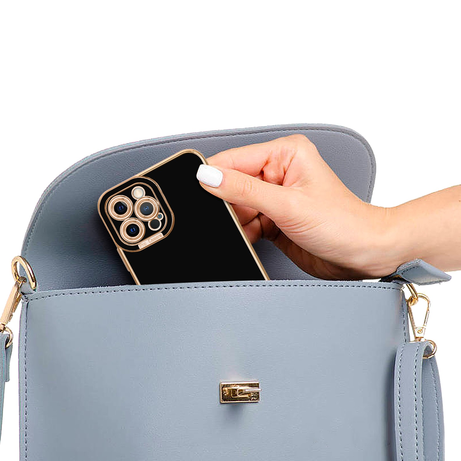 Eine Hand, die eine schwarze Handyhülle in eine blaue Handtasche legt. Die Hülle hat einen goldenen Rand.