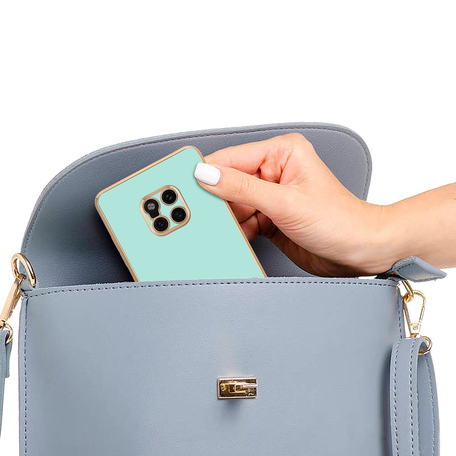 Hand zieht ein mintgrünes Telefon aus einer hellblauen Handtasche. Der Hintergrund ist weiß.