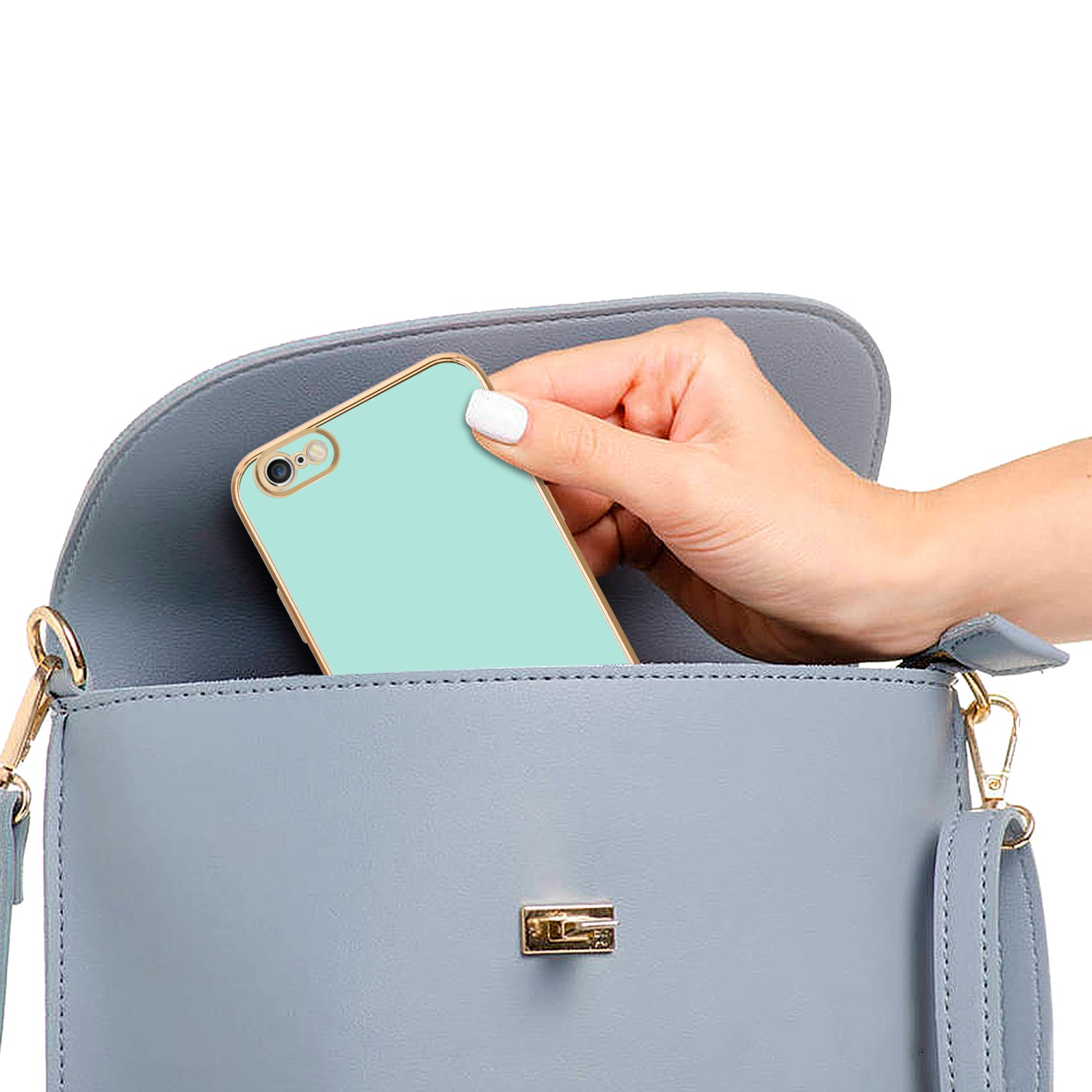 Hand legt mintgrünes Telefon in hellblaue Tasche mit Goldakzenten.