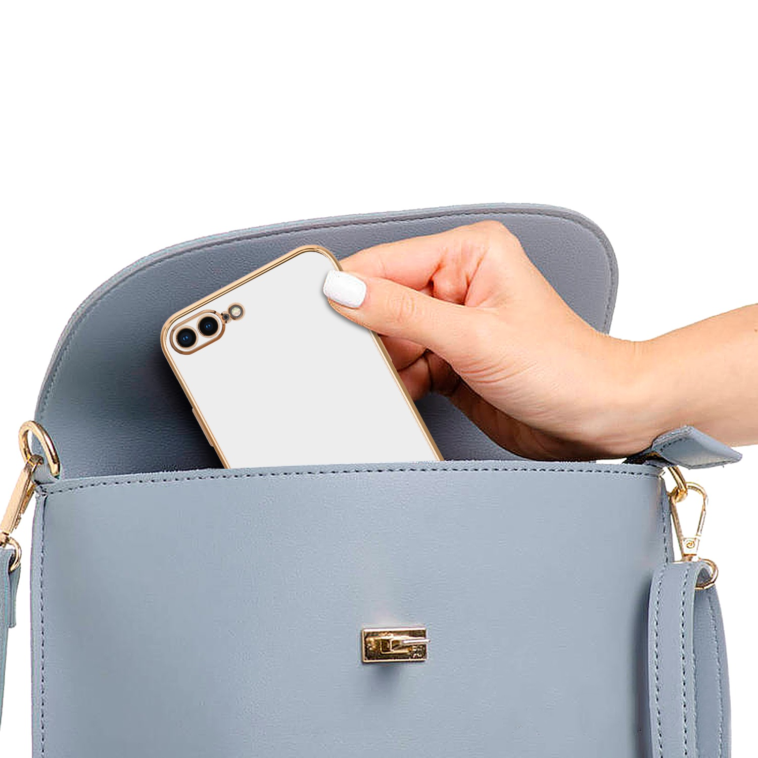 Eine Hand legt ein weißes Telefon in eine blaue Handtasche mit goldenem Rahmen.