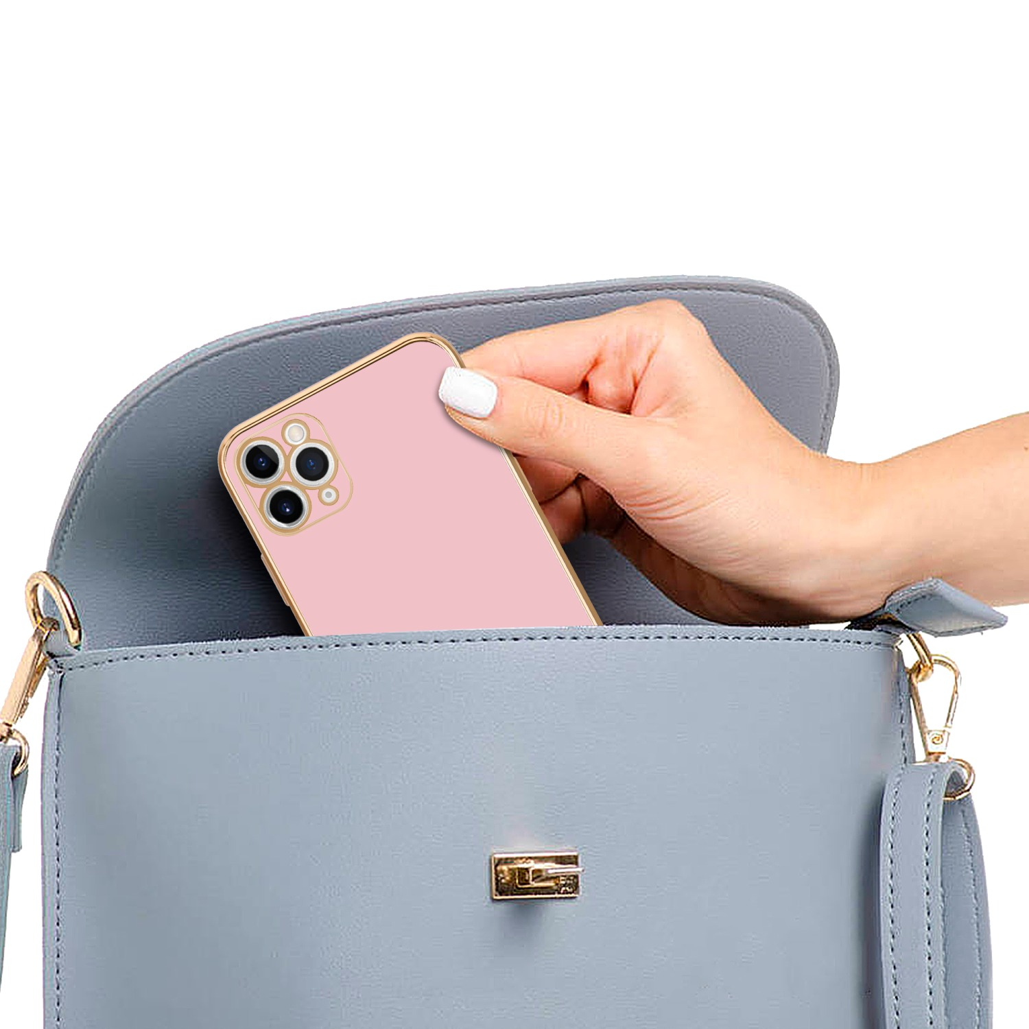 Ein rosa Telefon mit goldener Hülle wird von einer Hand in eine graue Handtasche gelegt.