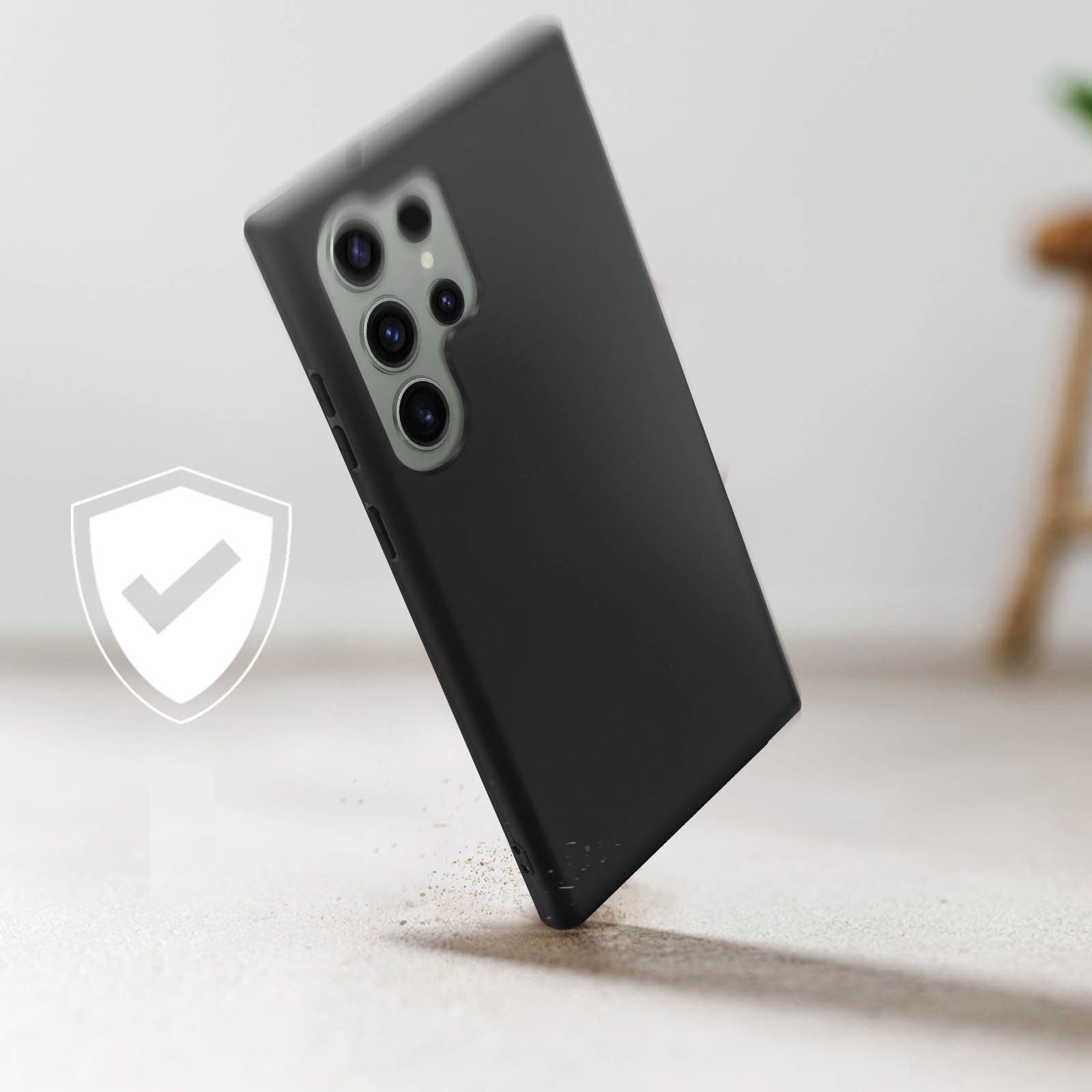 Coque de téléphone noire sur une surface. Un symbole de bouclier est à gauche. Un tabouret est à droite.