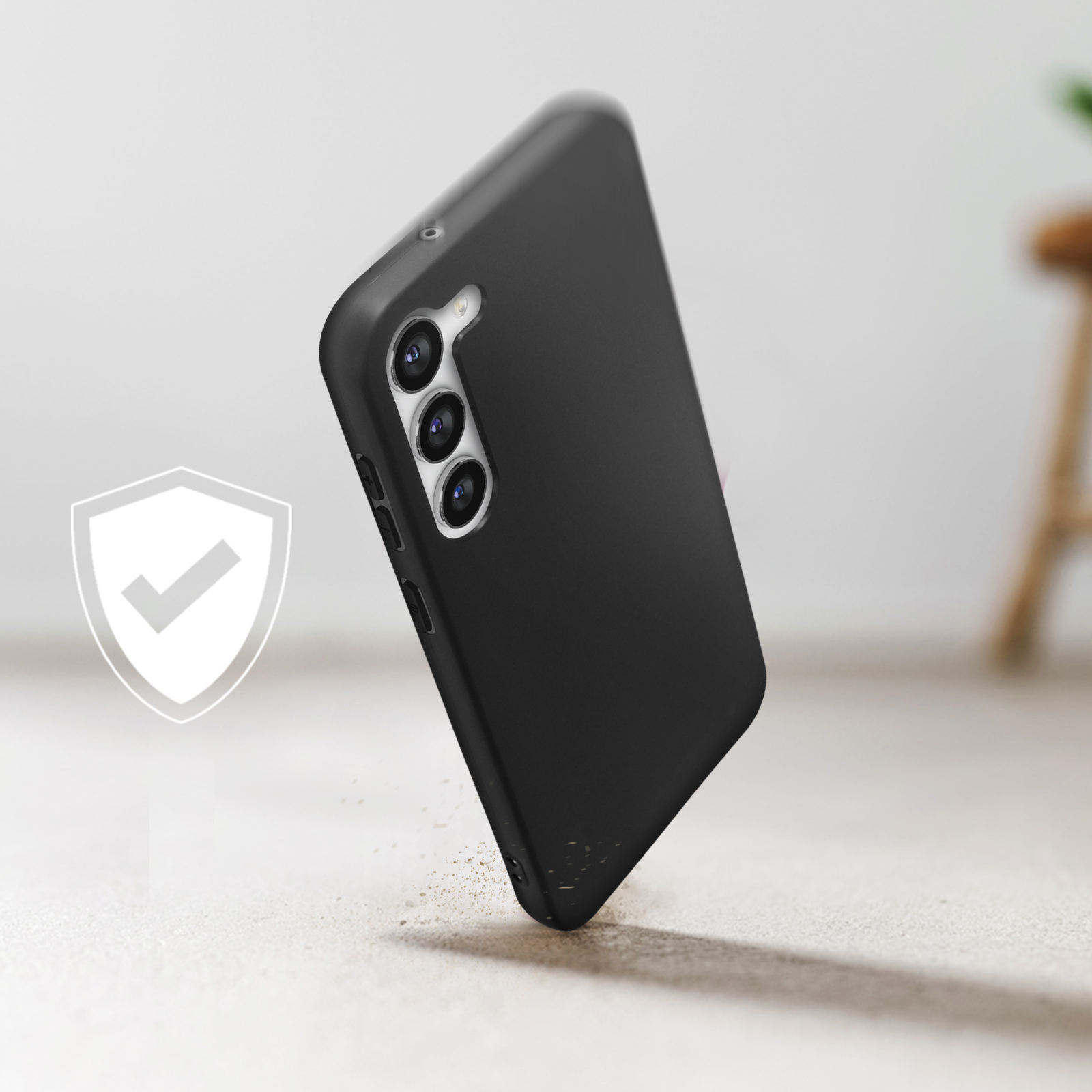 Coque de téléphone noire tombant, avec une icône de bouclier en arrière-plan.