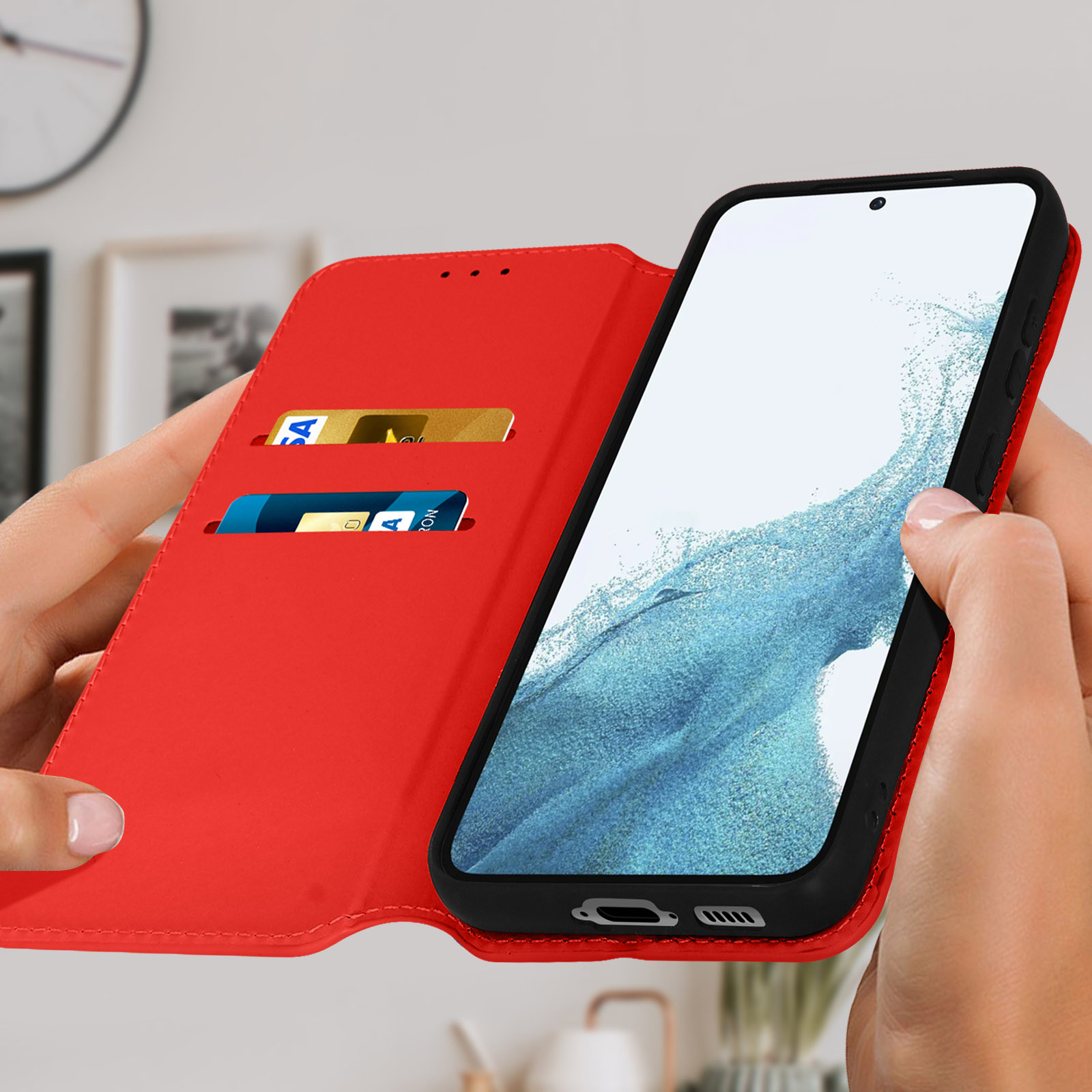 Une personne tient un étui de téléphone rouge ouvert. L'écran affiche une interface. L'étui a des fentes.