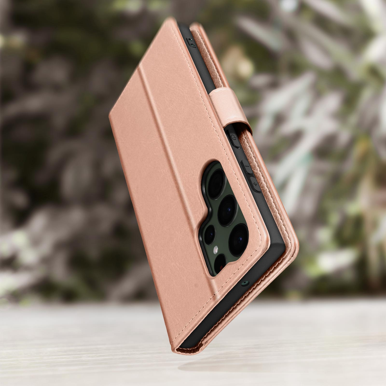 Een roze telefoonhoes, gesloten, op een standaard. De hoes is leerachtig en toont camera-uitsparingen.