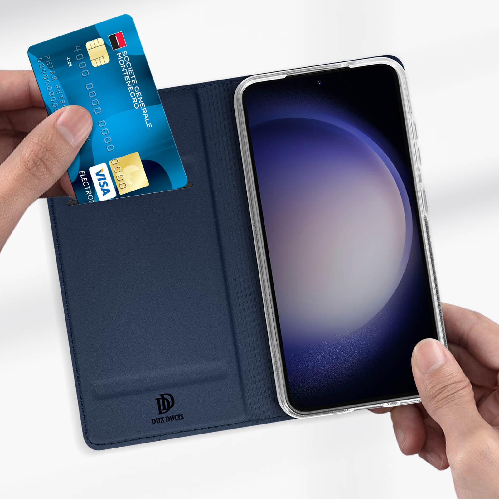 Una mano che tiene una carta di credito blu sopra una custodia per telefono blu scuro con un telefono.