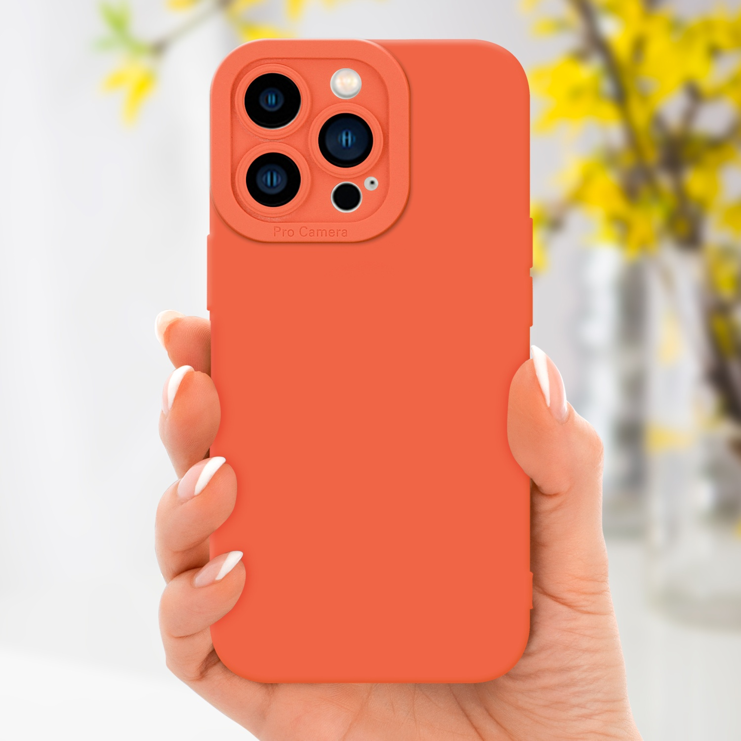 Mano che tiene una custodia arancione per telefono, fotocamera del telefono con testo pro camera, fiori gialli sullo sfondo.