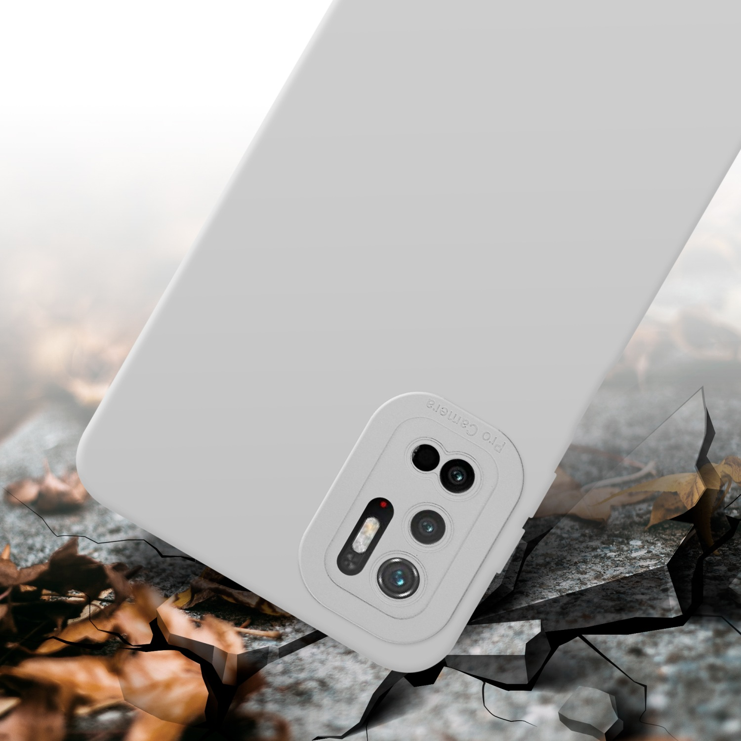 Custodia per telefono grigia con fotocamera. È su una superficie incrinata, con foglie.
