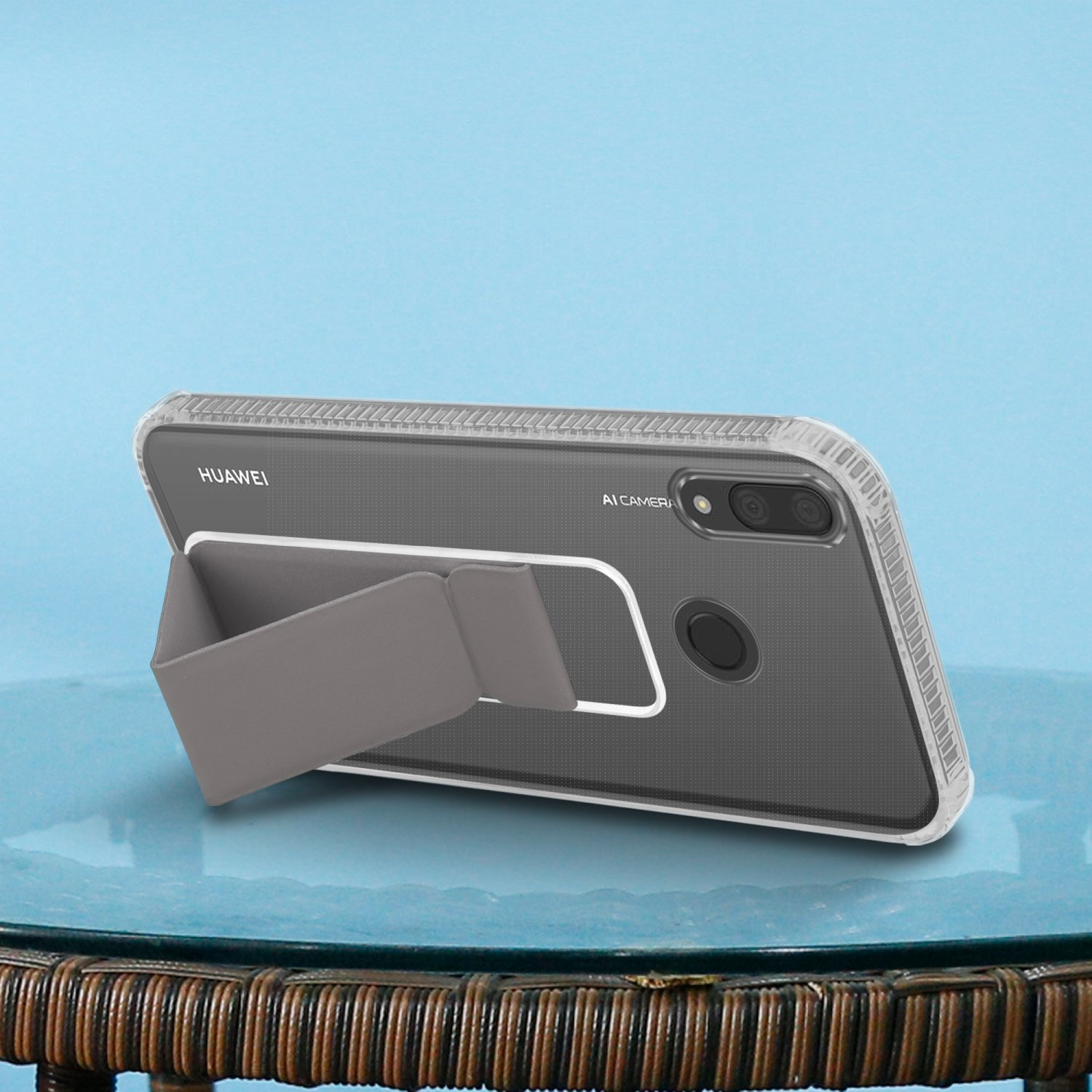 Graue Handyhülle mit Ständer. Telefon liegt auf einem Glastisch. Blauer Hintergrund.