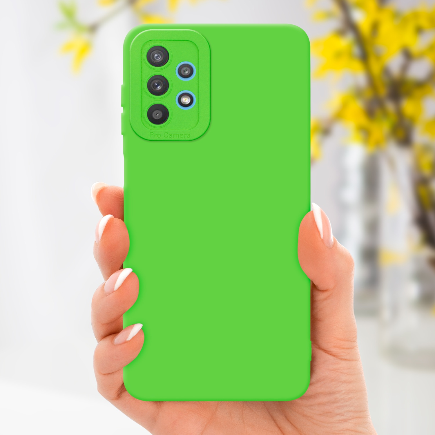 Mano che tiene una custodia verde per telefono con intaglio per fotocamera. Sfondo con fiori sfocati.