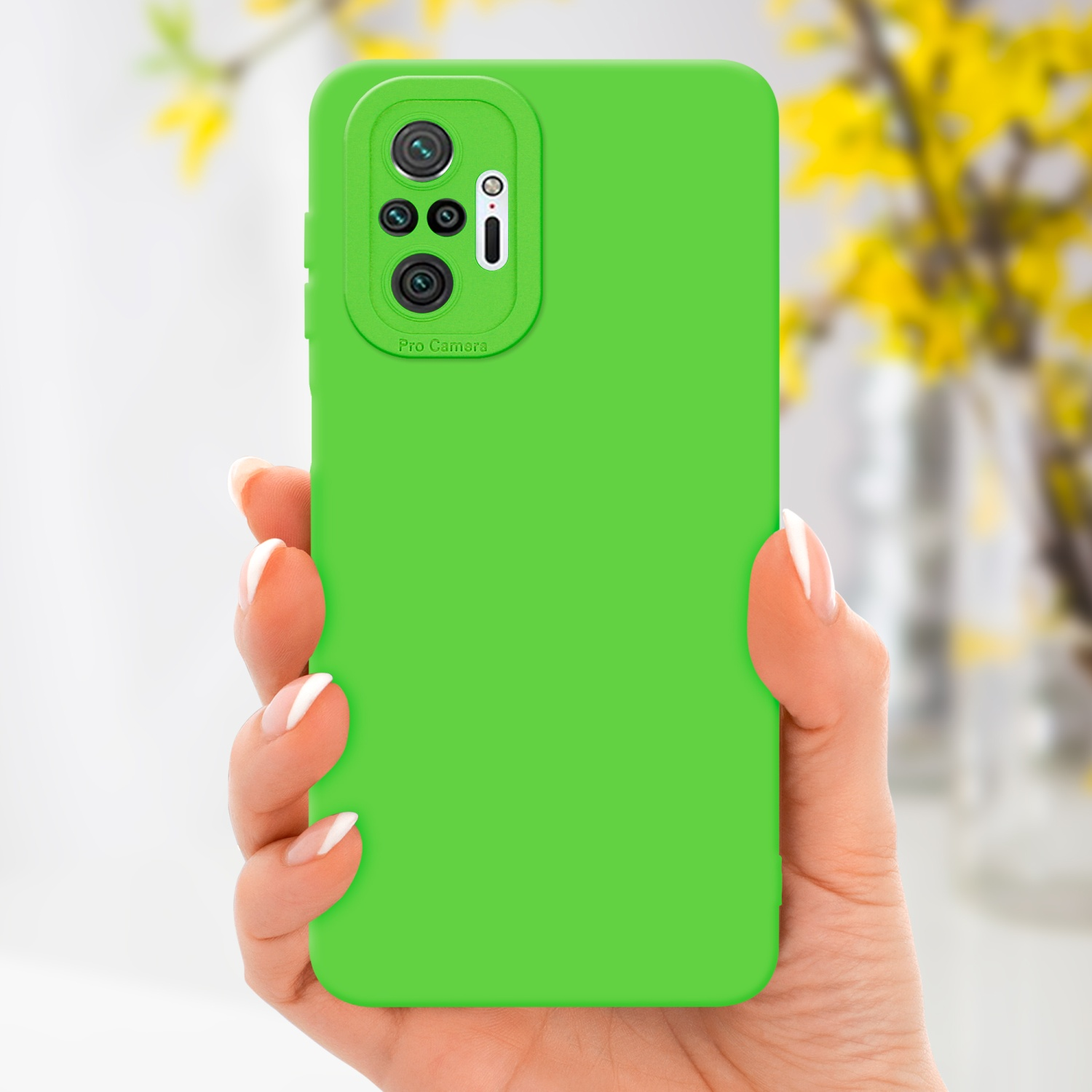 Una mano che tiene una custodia verde con protuberanza fotocamera. Fiori gialli sullo sfondo.