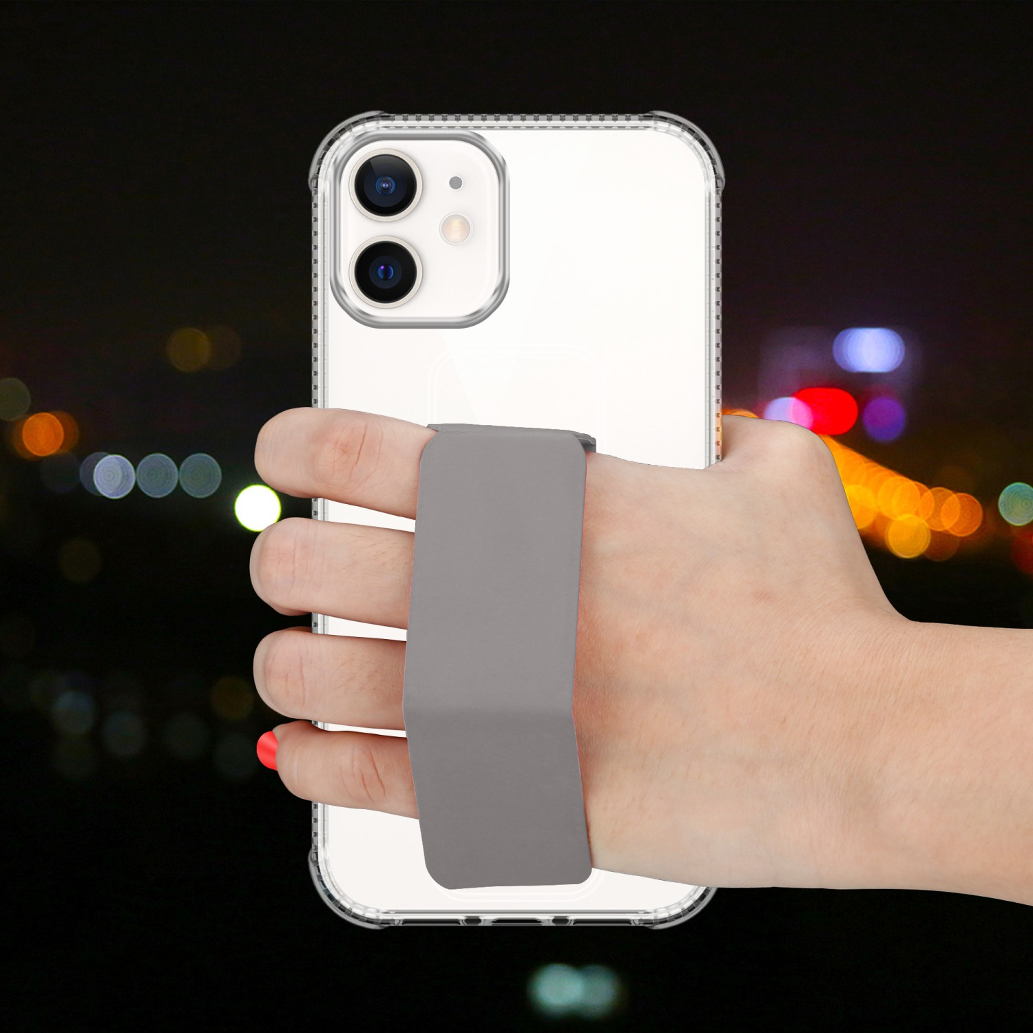Eine Hand, die ein Telefon mit grauem Riemen hält. Ein Nachthintergrund.