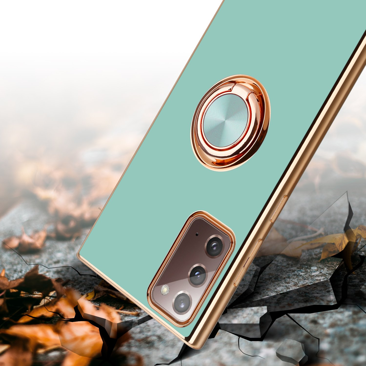 Custodia per telefono verde menta con anello dorato. È su una superficie incrinata, con uno sfondo sfocato.