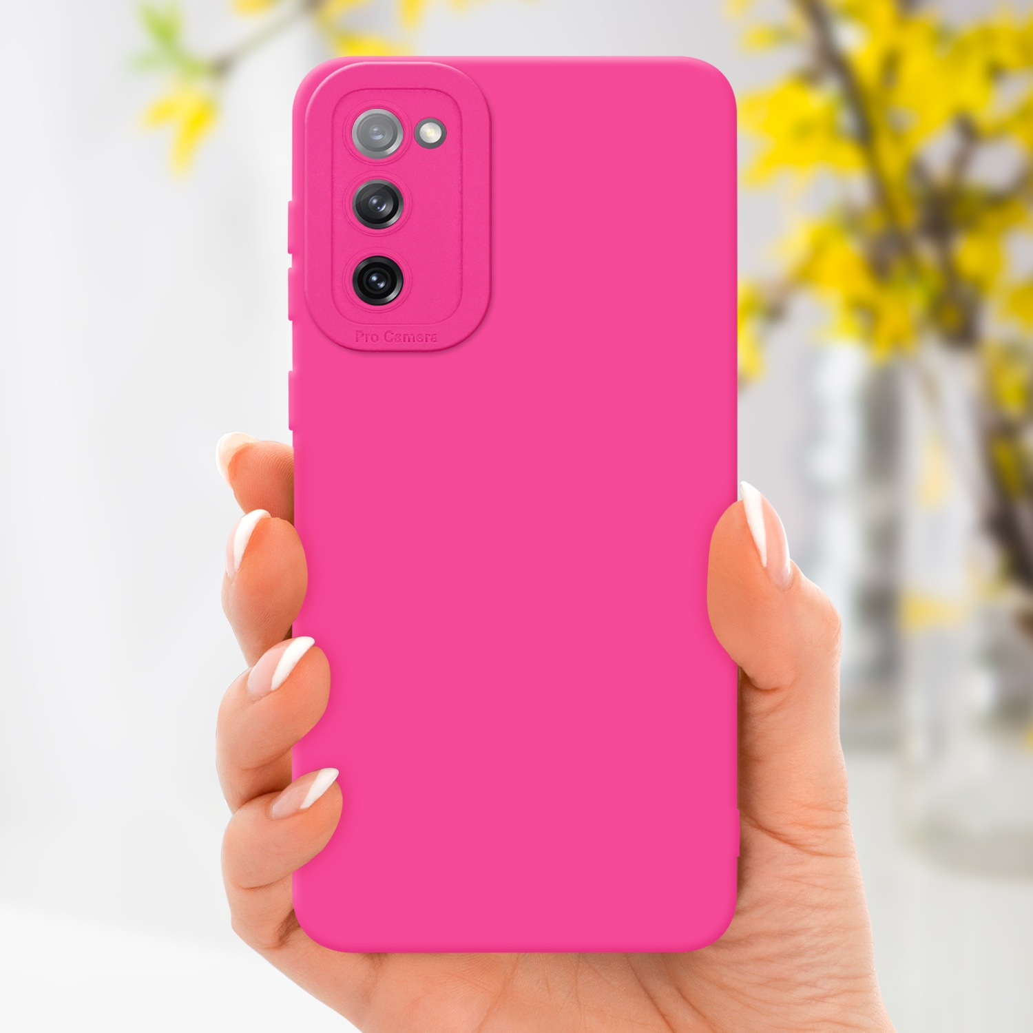 Custodia rosa per telefono tenuta in mano. Fiori gialli sullo sfondo. La custodia ha il modulo fotocamera.