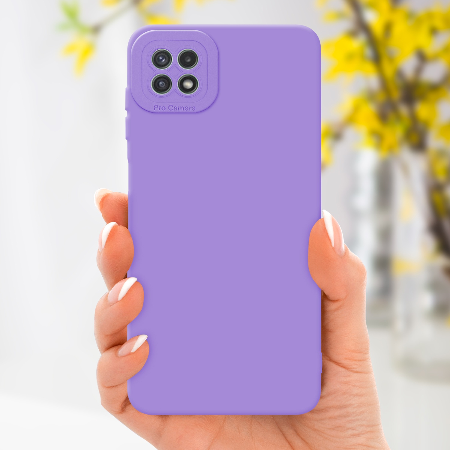 Main tenant coque violet clair avec caméra, fleurs en arrière-plan.