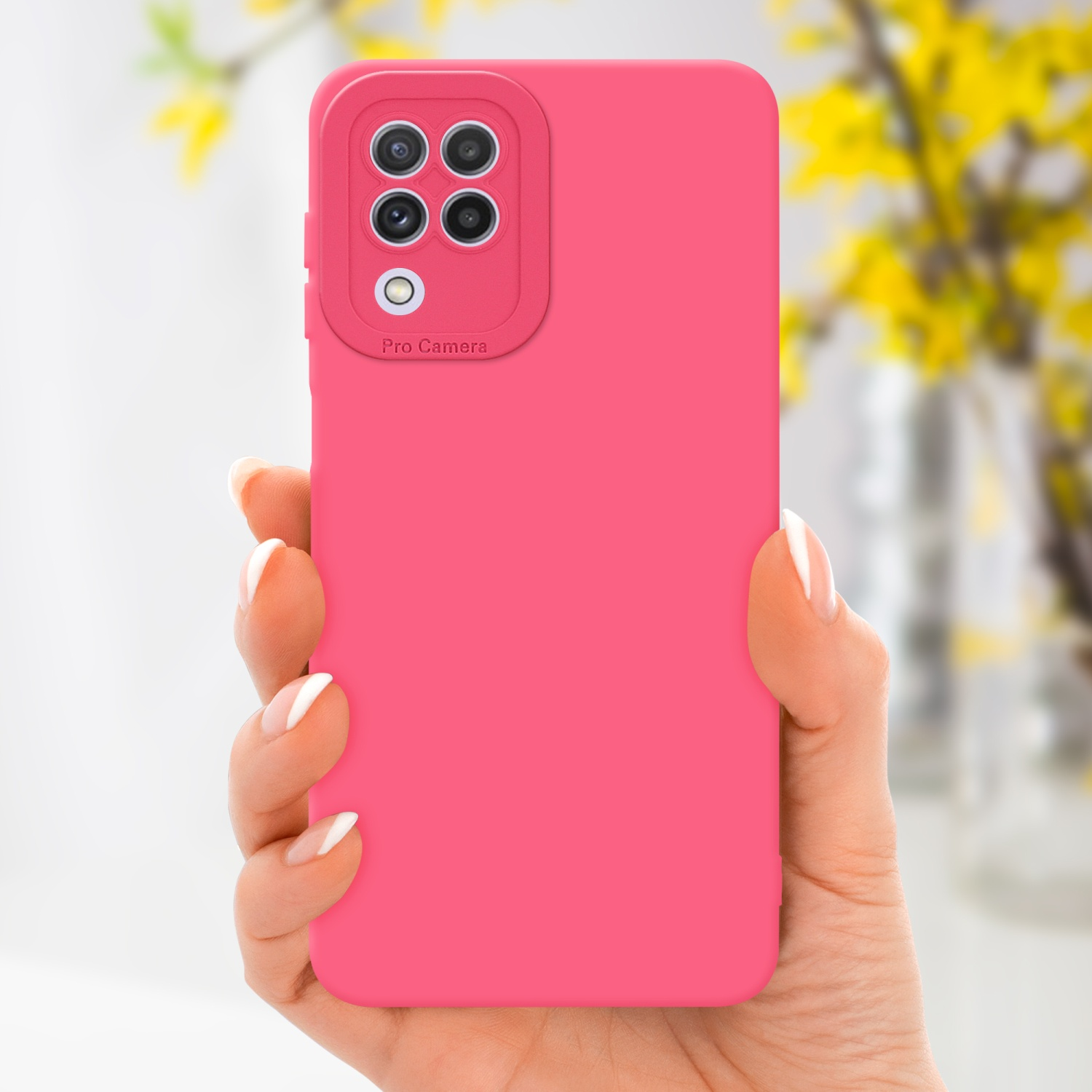 Una mano che tiene una custodia rosa per telefono con un ritaglio per la fotocamera. Fiori gialli sfocati sullo sfondo.