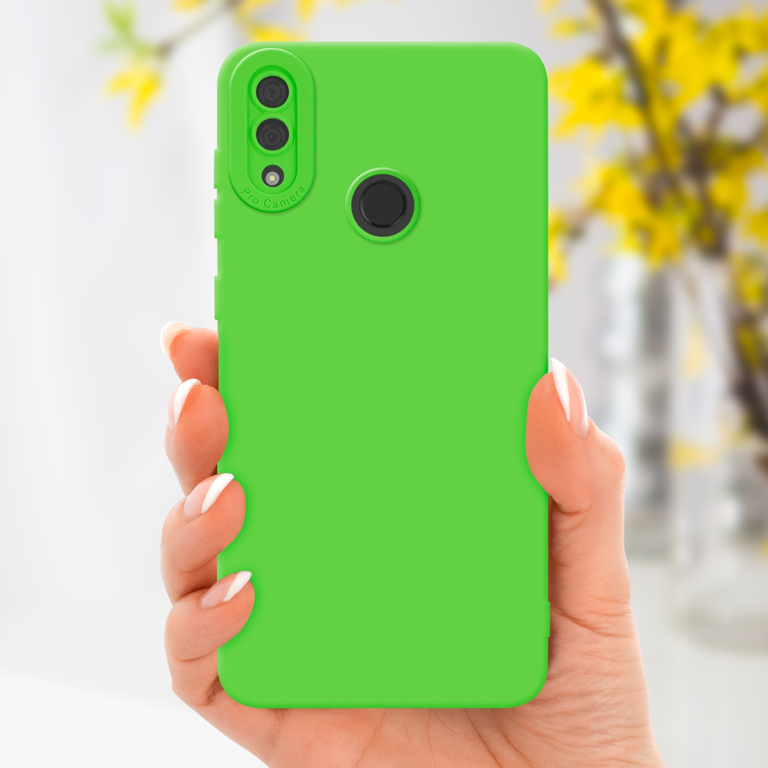 Main tenant une coque de téléphone verte. Fleurs jaunes floues en arrière-plan.